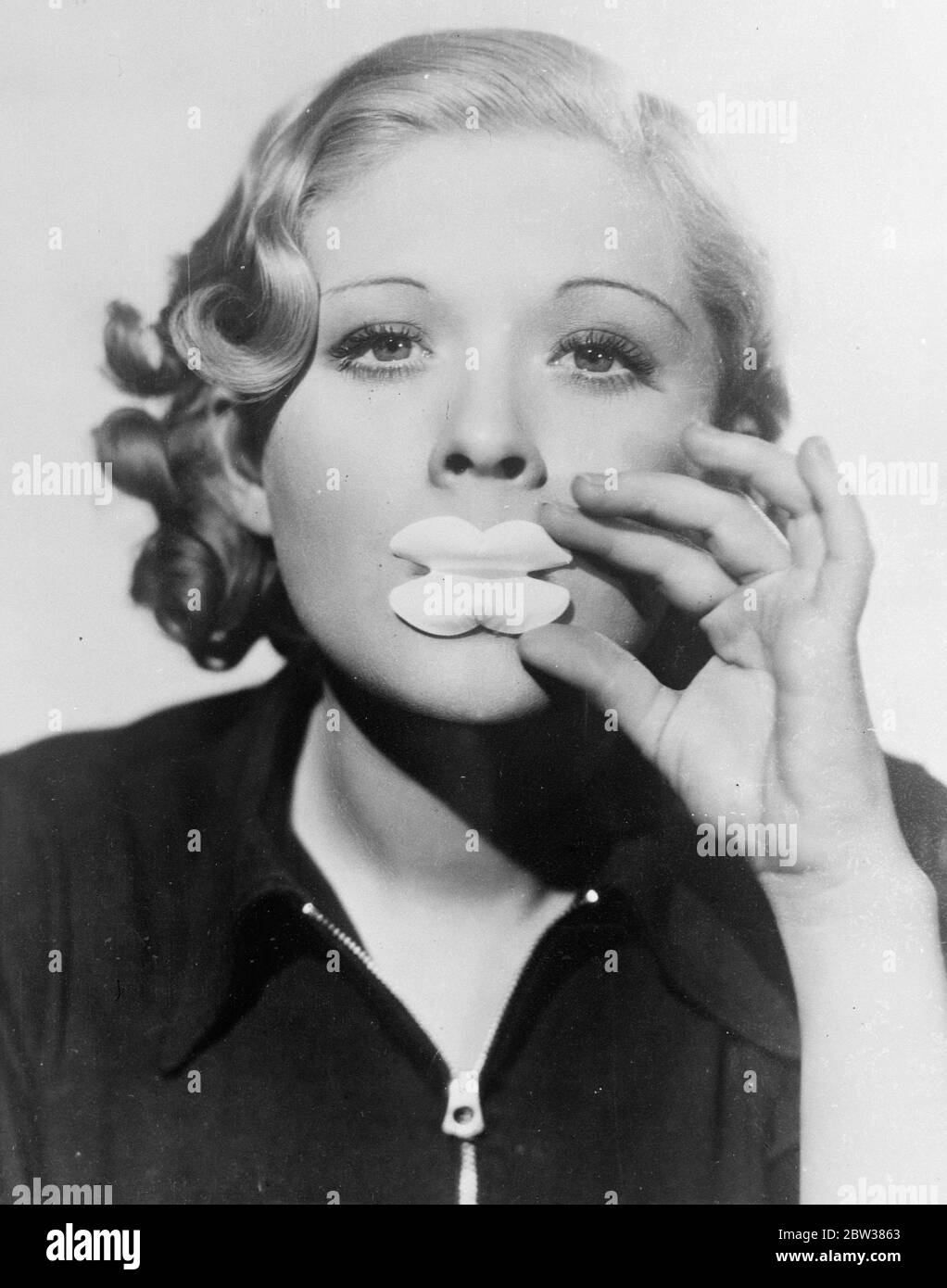 Anti-Lippenstift . Kleider jetzt nicht beschädigt werden. Um teure Stoffe zu sparen, die durch raue Lippen beschädigt werden, wenn Kleider angeprobt werden, hat ein Hollywood-Filmstudio ein neues Gerät eingeführt. Es nimmt die Form eines Schildes für die Lippen, die effektiv verhindert, dass die Rouge von Verschmutzung der Kleidungsstücke . Foto zeigt Dorothy Dell, die Bildschirmdarstellerin, demonstriert die neue Lippe Schild. 10 Mai 1934 Stockfoto
