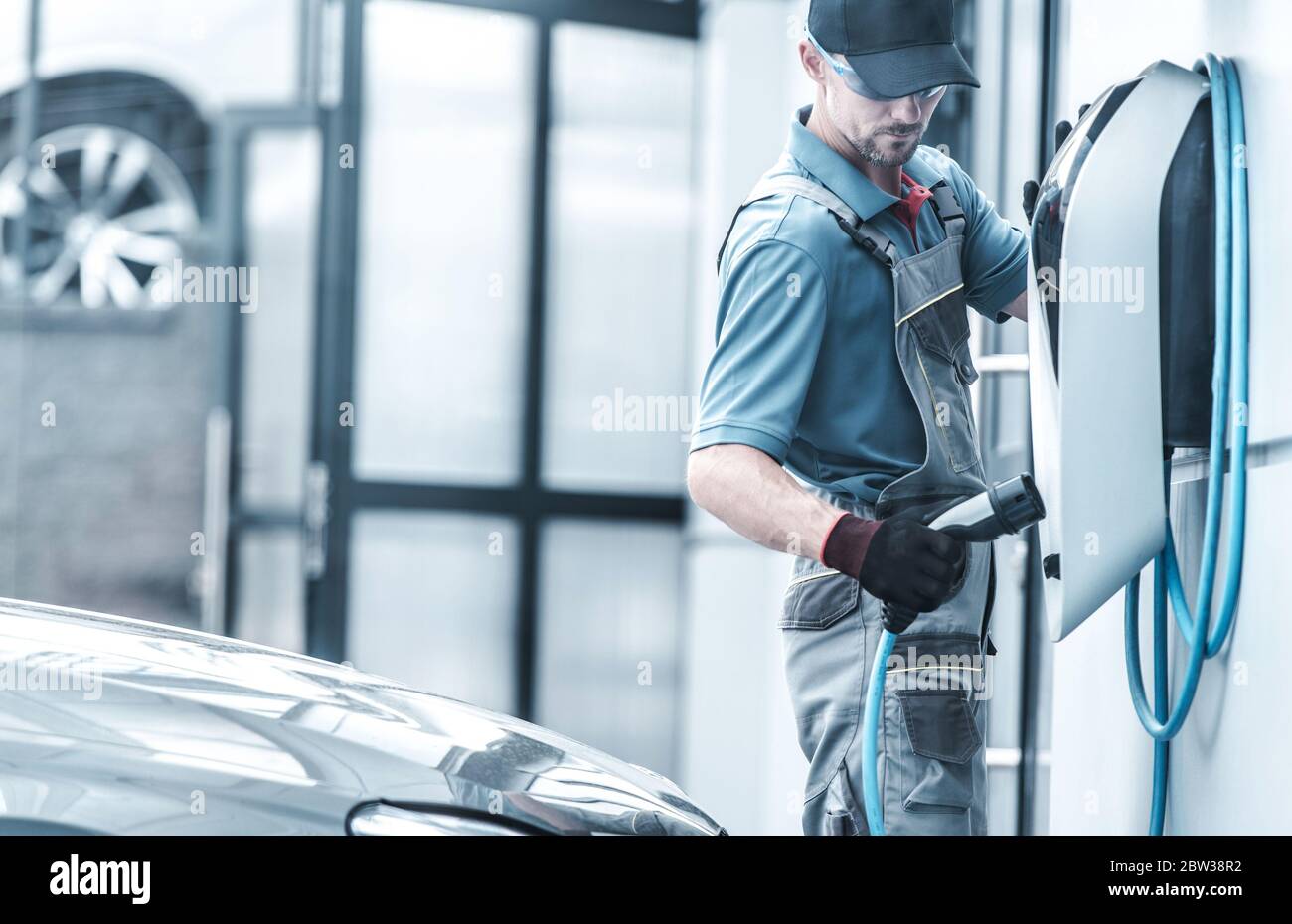 Kaukasische Kfz-Techniker Testen leistungsstarke elektrische Wand-Ladegerät für EV-Fahrzeuge laden. Kraftfahrzeuge mit alternativer Kraftstoffquelle. Stockfoto