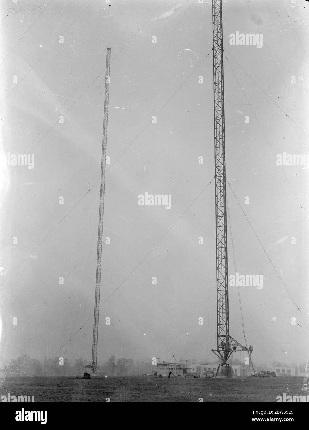 Neuer BBC-Riese nimmt Gestalt an Droitwich. Große Sender ' s 700 Fuß Antennentürme. Die großen 700 Meter hohen Stahlmasten, die höchste jemals von der BBC für die neue High-Power-Sender in Droitwich, Worcestershire, wurden nun abgeschlossen. Die Station, die von einem "Hush Hush" Luft umgeben ist, wird im Sommer betriebsbereit sein. Eine Luftstärke von bis zu 200 Kilometern ist von diesem nationalen Sender zur Verfügung und das ist Macht genug, um die meisten der europäischen Sendungen zu ziehen. Jeder der Antennenmasten wird senkrecht durch 21 Stahlseile gesichert, verankert Stockfoto
