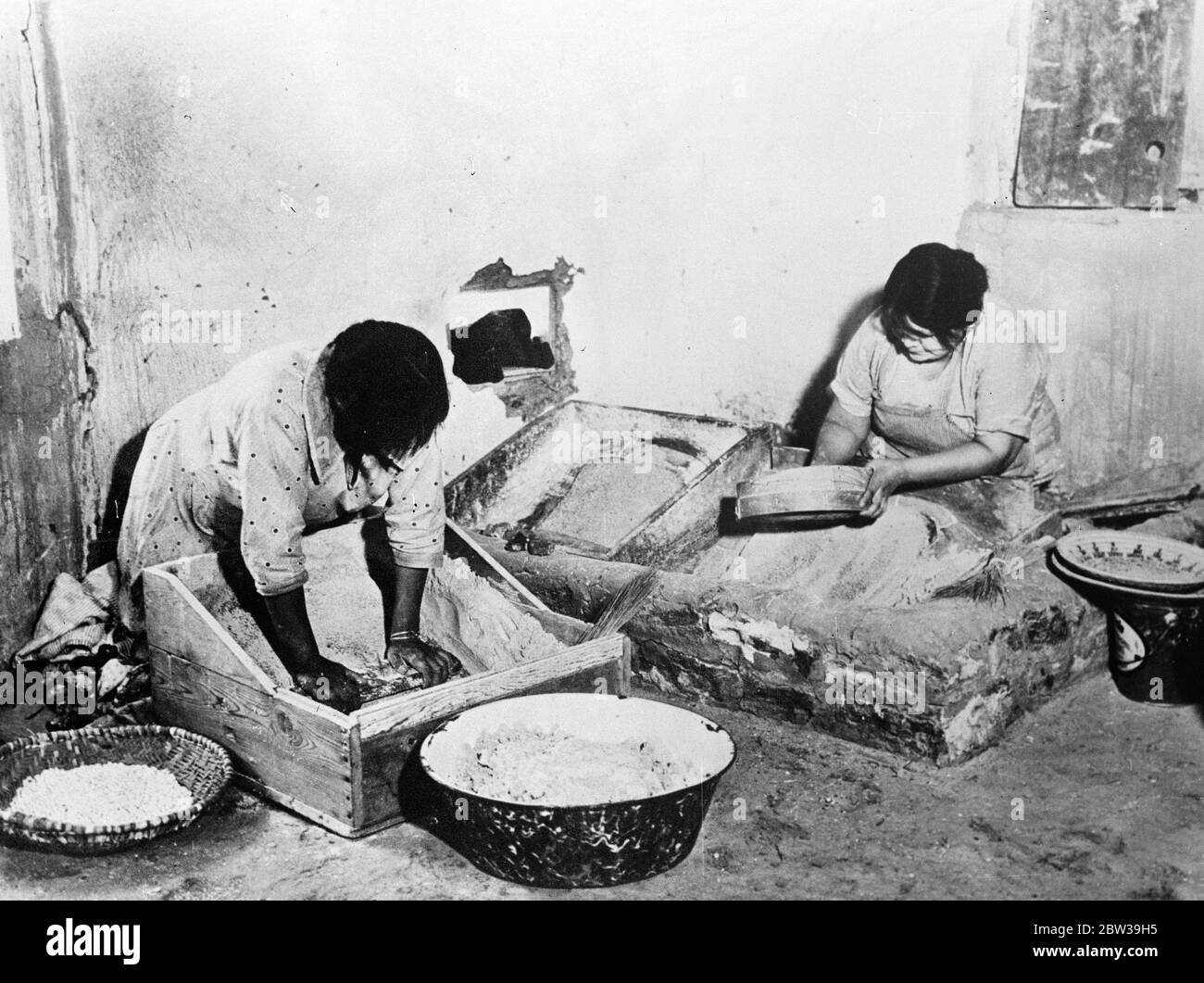 Original Caption: Primitive Bäckerei - uralte Bräuche überleben unter den Indianerstamm des Grand Canyon. Navajo Indische Frauen des Grand Canyon , Amerika , Mahlen von Mais und Brot in ihrer primitiven Bäckerei . Trotz des fortschritts sind die Methoden, die verwendet werden, genau die gleichen wie die von den Indianern Jahrhunderte vor. 1935 Stockfoto