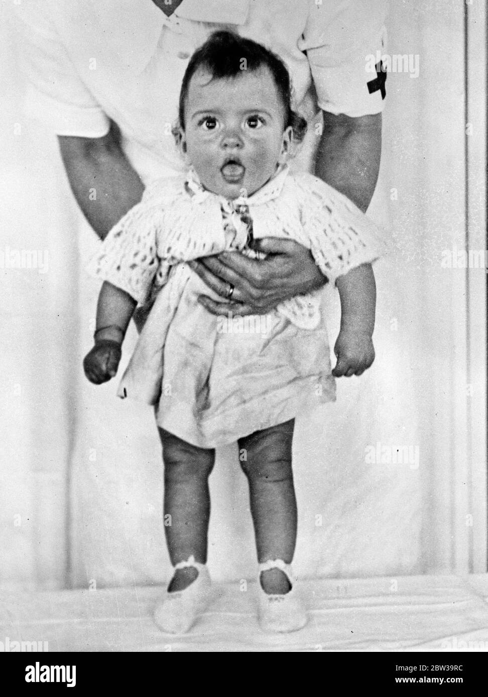 Erste Schritte der dionne Quintlete . Es gibt jetzt große Aufregung in der Dionne Quinuplets Privatklinik in Callender, Ontario, weil die fünf Mädchen sind ihre ersten zaghaften Schritte. Foto zeigt Cecilie öffnet ihren Mund, während sie sanft aufrecht von der Krankenschwester de Kiriline steht. 18 Juli 1935 . Stockfoto