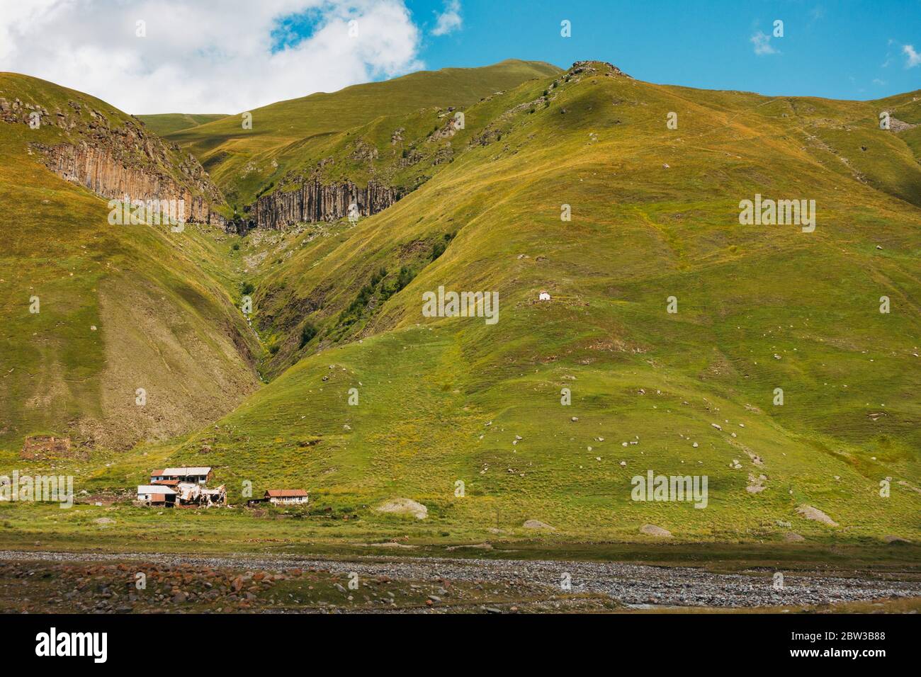 Einige Häuser auf einem grasbewachsenen Hügel in Shewardeni, Kazbegi, Georgia, während der Sommerzeit Stockfoto