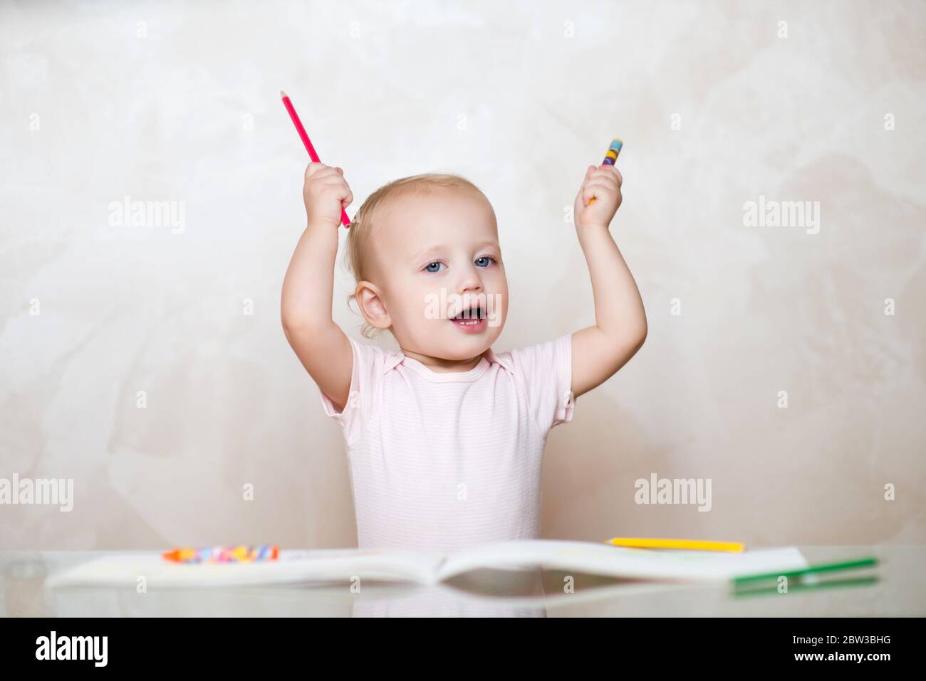 Kleines Mädchen mit einem Bleistift und einem Buntstift in den Händen Stockfoto