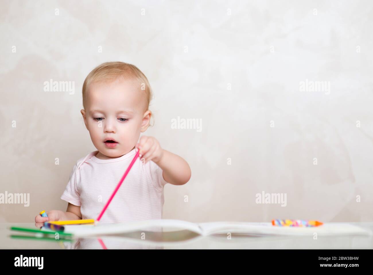 Baby zeichnet eine Linie mit einem rosa Bleistift in einem Album. Kopierbereich Stockfoto
