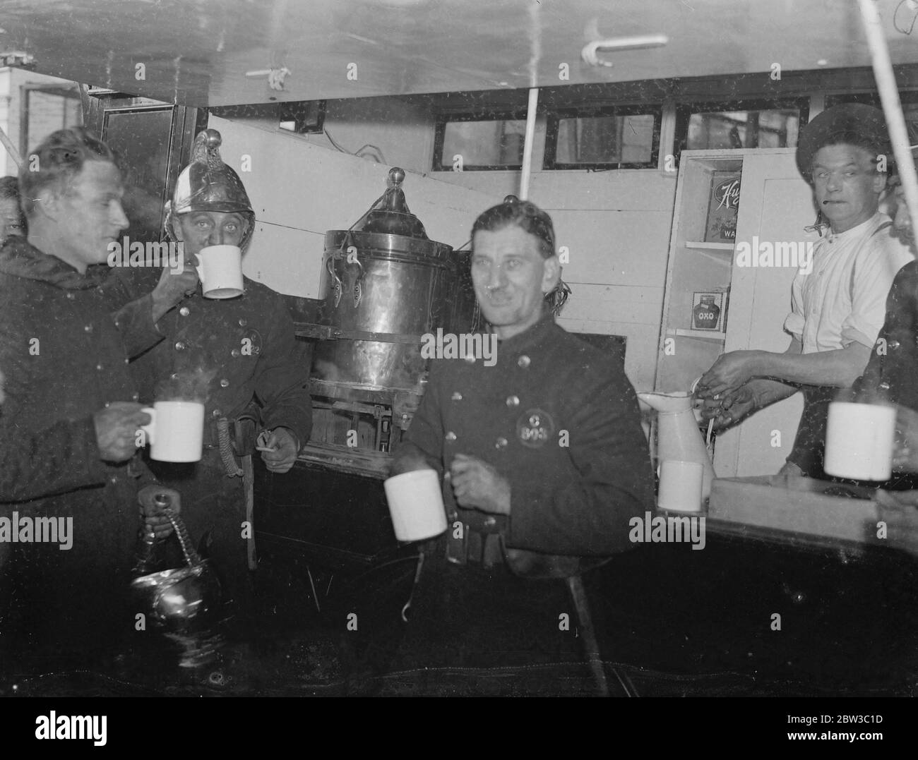 Feuerwehrleute erfrischend sich mit einer Tasse Tee nach der Bekämpfung von Abfällen Gummi Feuer. 29. Oktober 1934 Stockfoto