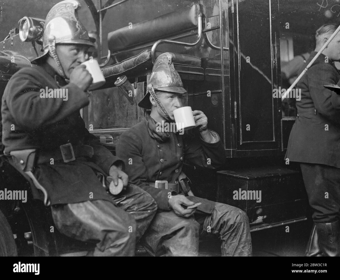 Feuerwehrleute erfrischend sich mit einer Tasse Tee nach der Bekämpfung von Abfällen Gummi Feuer. 29. Oktober 1934 Stockfoto