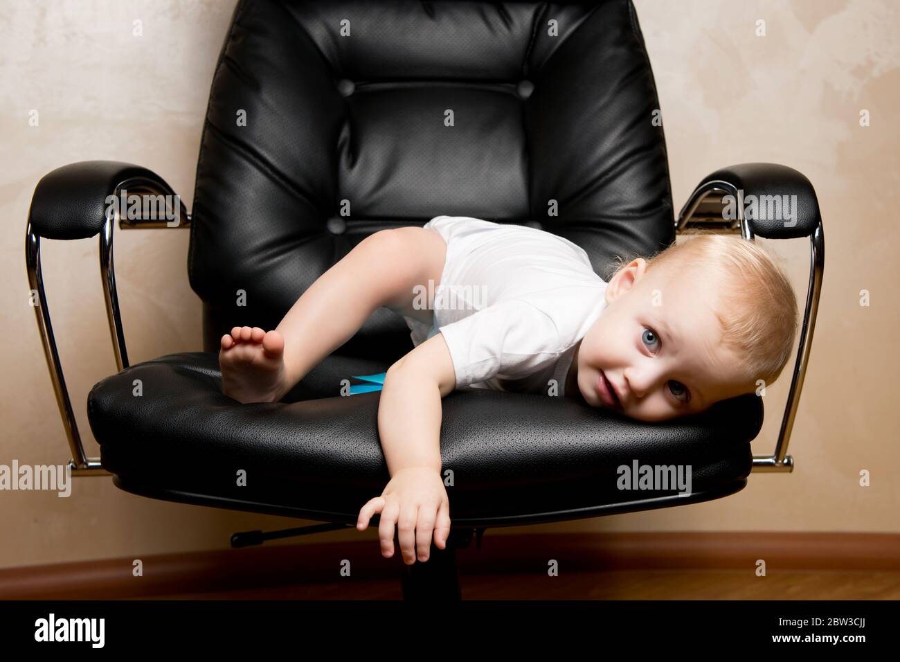 Kind spielt auf einem großen Bürostuhl kriechen Stockfoto