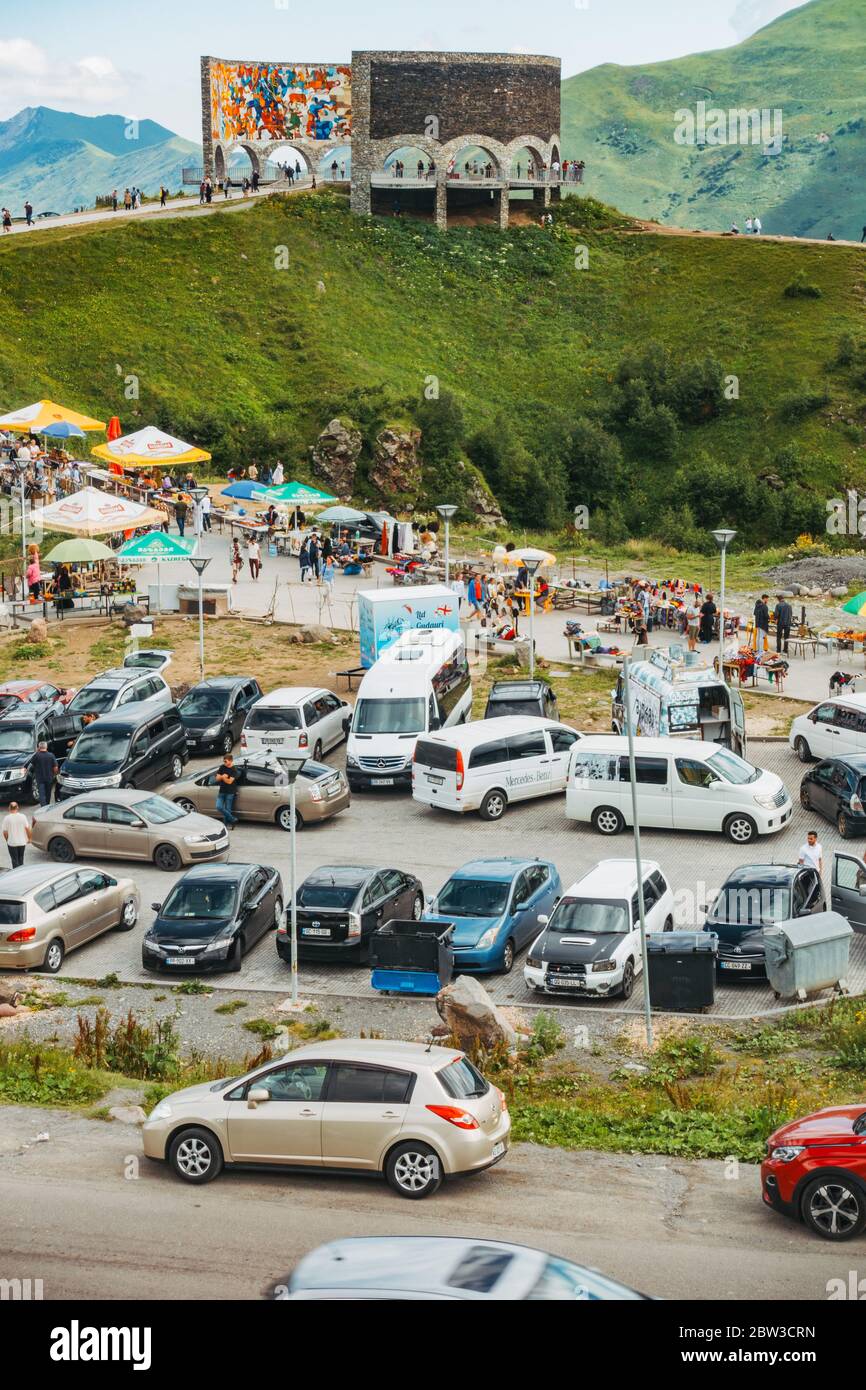 Ein vollgepackter Parkplatz, während Touristen besuchen die Russland-Georgien Freundschaftsdenkmal in den Kaukasus-Bergen, Georgien. Erbaut 1983 Stockfoto