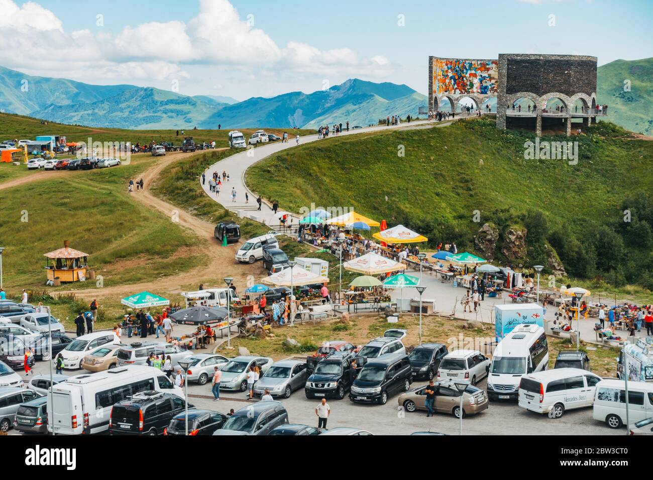 Ein vollgepackter Parkplatz, während Touristen besuchen die Russland-Georgien Freundschaftsdenkmal in den Kaukasus-Bergen, Georgien. Erbaut 1983 Stockfoto