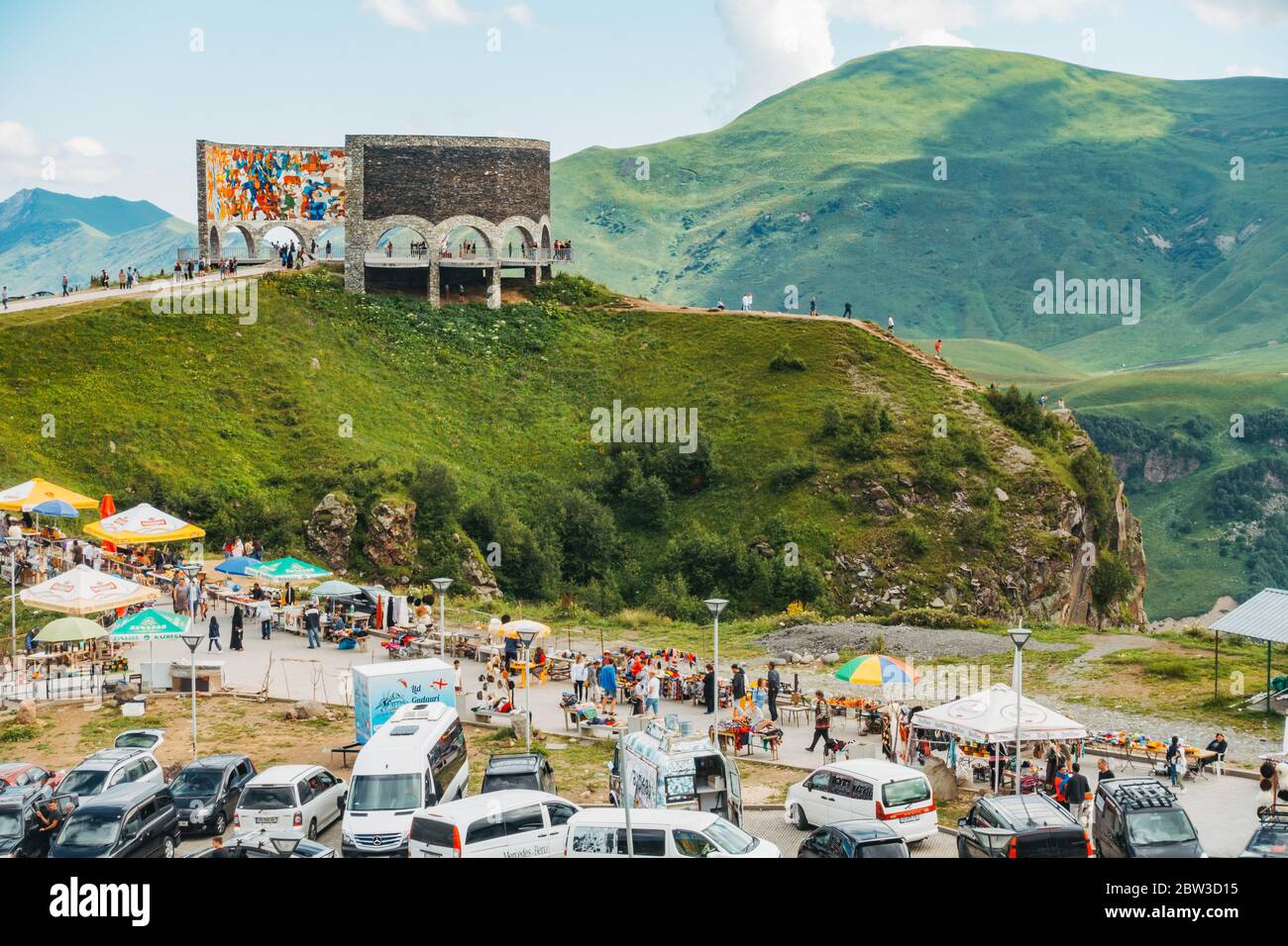 Ein vollgepackter Parkplatz, während Touristen besuchen die Russland-Georgien Freundschaftsdenkmal in den Kaukasus-Bergen, Georgien. Erbaut 1983 Stockfoto