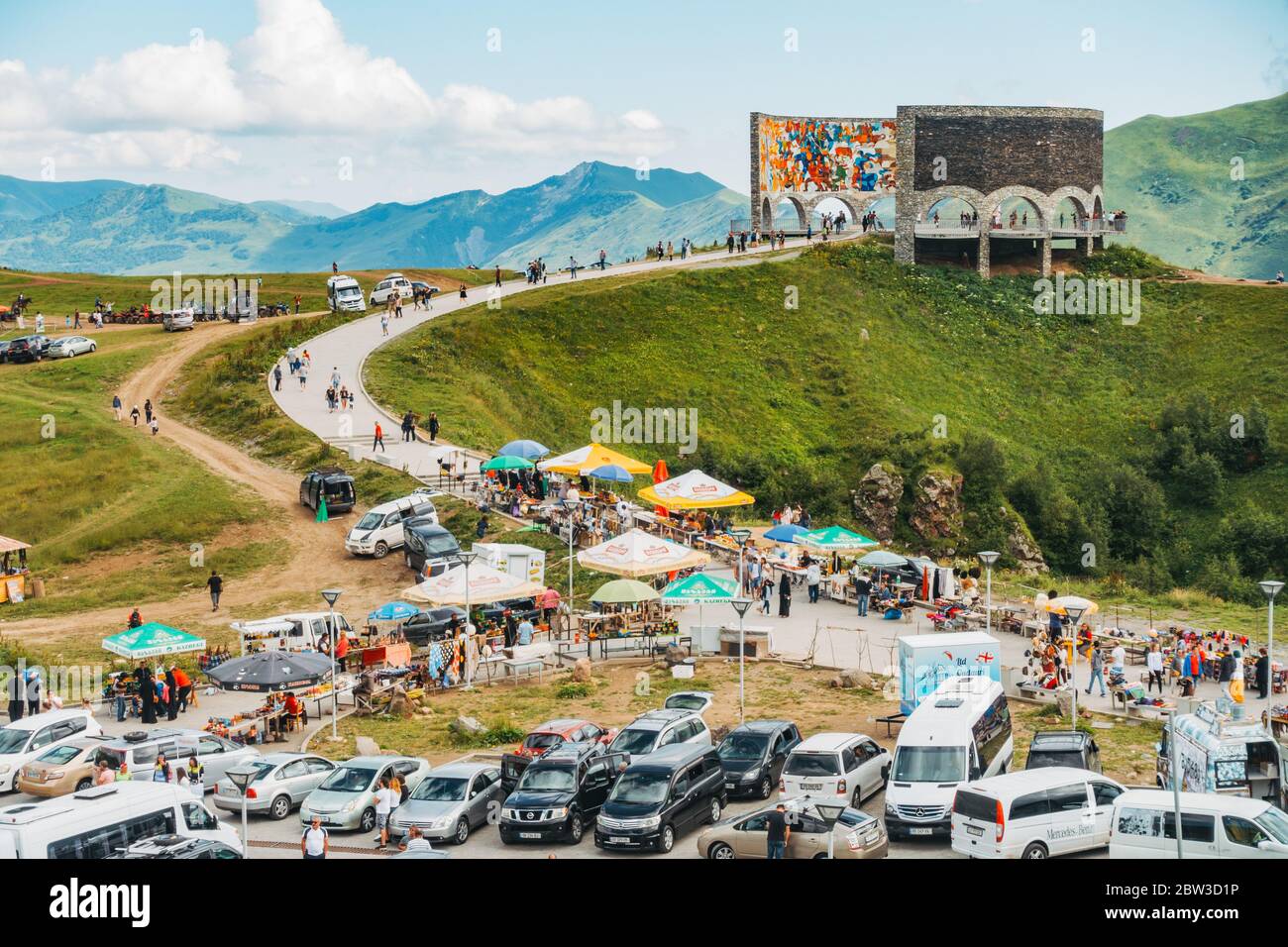 Ein vollgepackter Parkplatz, während Touristen besuchen die Russland-Georgien Freundschaftsdenkmal in den Kaukasus-Bergen, Georgien. Erbaut 1983 Stockfoto