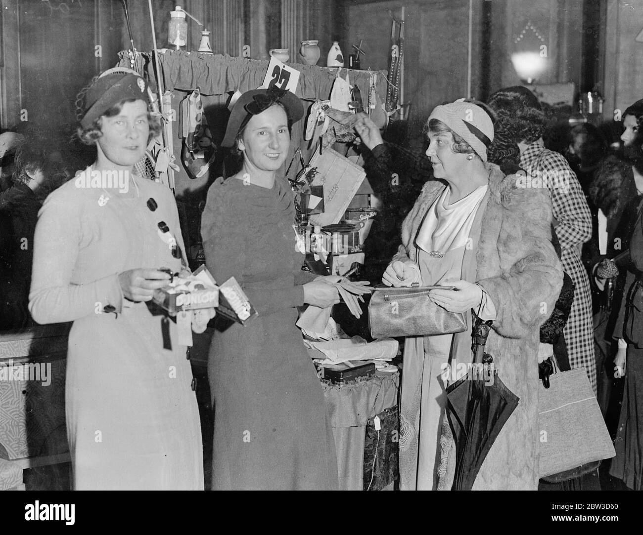 Dorothy Round und Molly Gourlay als Stallhalter auf dem Londoner Producemarkt. Miss Dorothy Round verkauft ein Paar Handschuhe an einen Kunden an ihrem Stand . Links ist Miss Molly Gourlay. 21. November 1935 Stockfoto