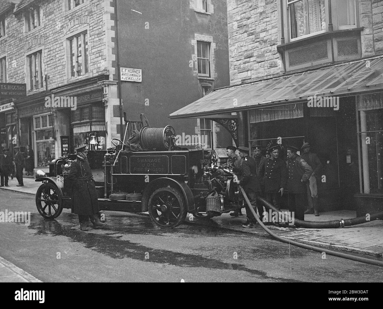 Die Feuerwehr pumpt Wasser aus den Geschäften nach einem schweren Hochwasser in Swanage . Feuerwehrleute Pumpen das Wasser aus einem überfluteten Geschäft in der High Street in Swanage, Dorset. 19. November 1935 Stockfoto