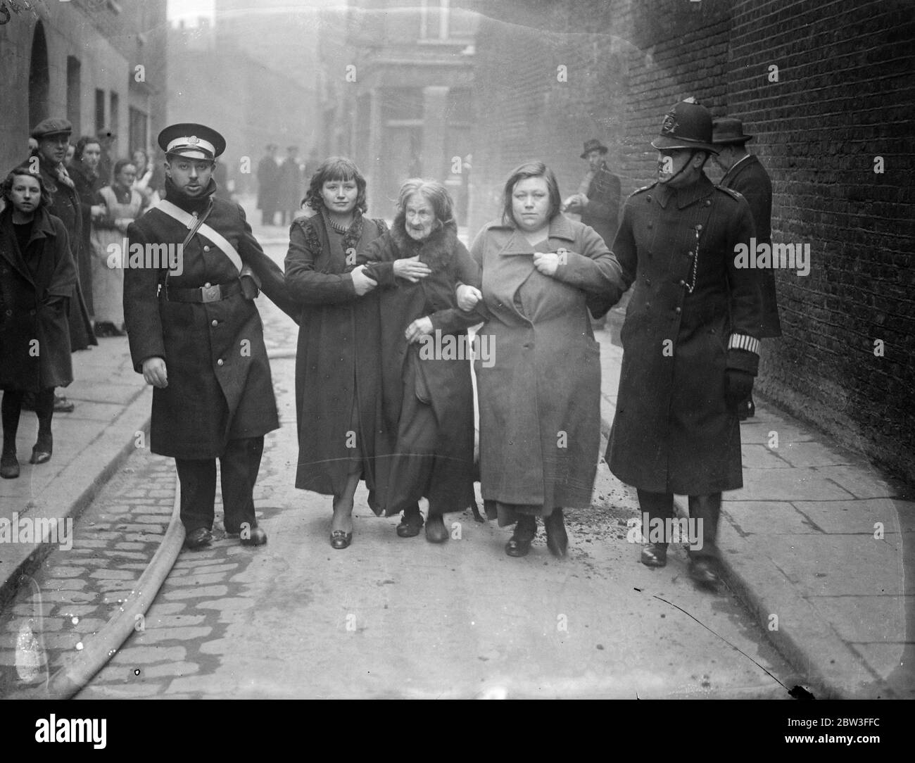 Polizei und die St. John Ambulance Brigade begleiten notleidende Hausbesitzer während der Wapping-Gasarbeiten aus der Gefahrenzone. 26. Januar 1935 Stockfoto