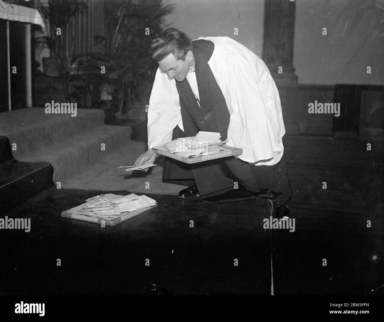 Verkrüppelte Männer und Frauen besuchen den ersten Glaubensheilungsgottesdienst, der in Brighton gefeiert wird. Foto zeigt ; der Reverend John Maillard platziert einige der Hunderte von Briefen erhielt er gebeten, für Krüppel nicht in der Lage, den Gottesdienst zu besuchen beten , auf dem Altar in der Kirche St. Stephens . 25. Januar 1935 Stockfoto