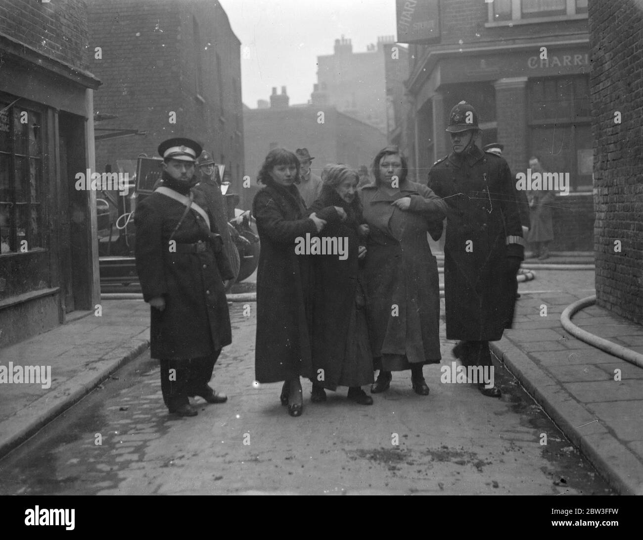 Polizei und die St. John Ambulance Brigade begleiten Haushalter aus der Gefahrenzone während der Wapping Gas Works lodern. 26. Januar 1935 Stockfoto