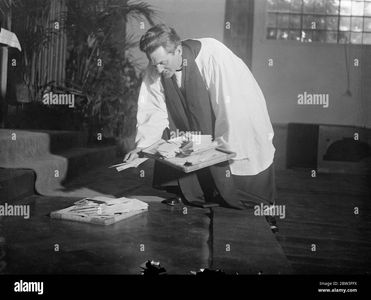 Verkrüppelte Männer und Frauen besuchen den ersten Glaubensheilungsgottesdienst, der in Brighton gefeiert wird. Foto zeigt ; der Reverend John Maillard platziert einige der Hunderte von Briefen erhielt er gebeten, für Krüppel nicht in der Lage, den Gottesdienst zu besuchen beten , auf dem Altar in der Kirche St. Stephens . 25. Januar 1935 Stockfoto