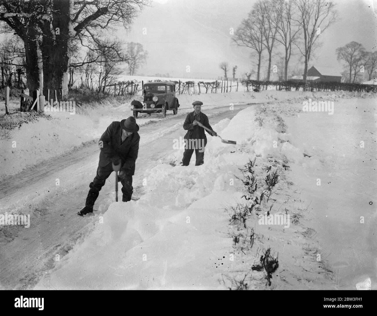 Schneewehen halten den Verkehr in Hertfordshire. Foto zeigt ; Männer, die die Straßen von Schnee. 27. Januar 1935 Stockfoto