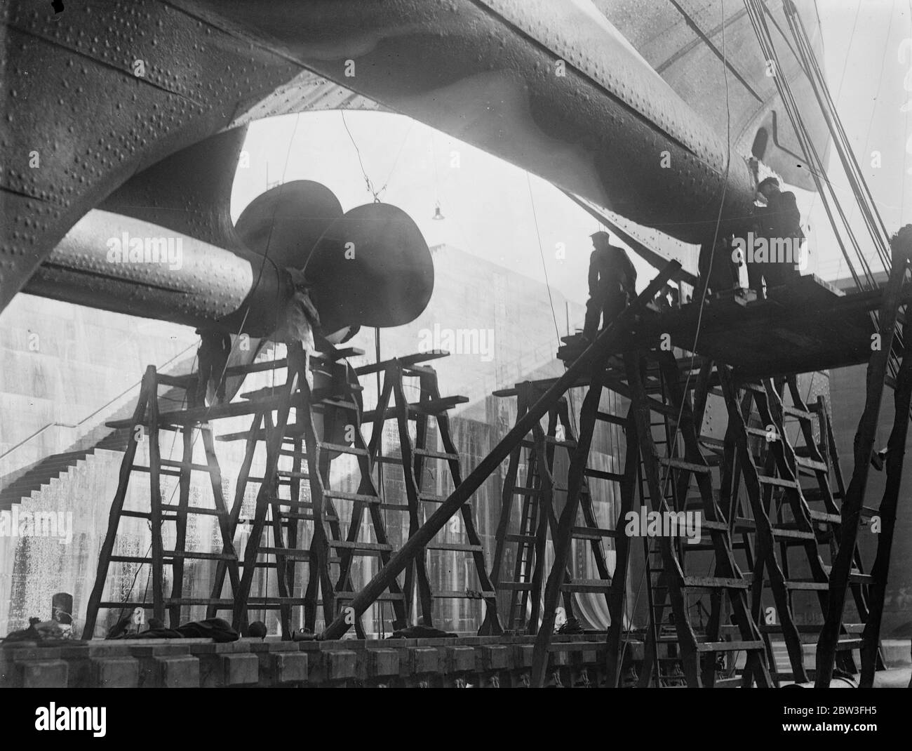 Foto zeigt einen Arbeiter, der in die mächtigen Treibschächte der SS Majestic eingeht, während sie in der riesigen Gravierstation in Southampton ruht. 29. Januar 1935 Stockfoto