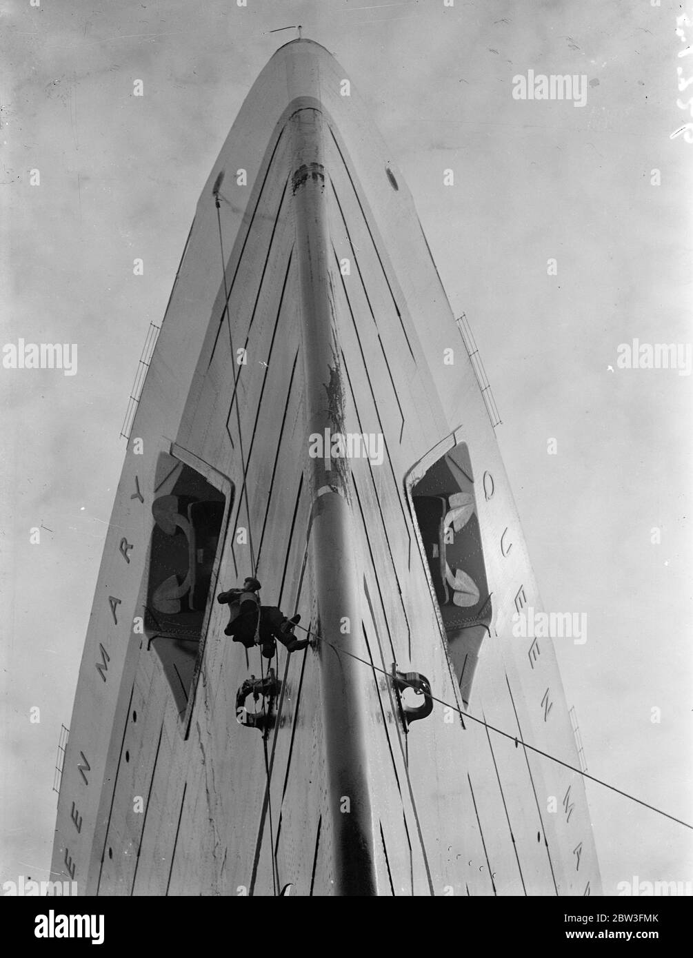 Maler ' s großen Job ! . Nun, da die "Queen Mary" im Trockendock ist, wird der kolossale Großteil des riesigen Liners im Vergleich zu der kleinen Armee von Malern und Handwerkern bei der Arbeit an ihrem Rumpf zu Vorteil gezeigt, Die wird in Vorbereitung für die nächsten Woche geschabt und bemalt. Die Propeller, die sie von Clyde herunterbrachten, wurden für andere von einem corsar-Pitch geändert. Foto zeigt, kriechend über die hoch aufragenden Bögen wie eine Fliege der Maler erneuert die Unterwassermarkierungen auf dem Rumpf der Queen Mary ' s in Southampton. 31 März 1936 Stockfoto