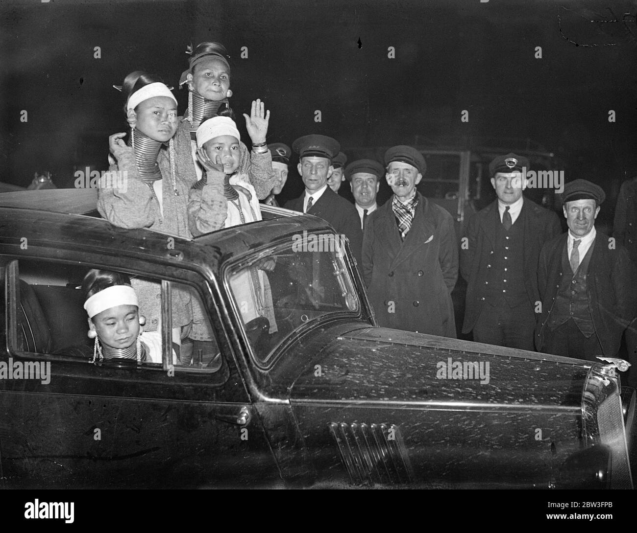 Sie fanden das Sonnendach unschätzbar. Giraffen Hals Frauen kommen in London. Eine Reihe von Giraffen necked Frauen von Burma angekommen Victoria Station von Paris zu Bertram Mills Zirkus auf seiner Sommer "Tenting" Tour zu verbinden. Die durchschnittliche Länge des Halses erreicht bis zu sechzehn Zoll. Die Padaung Mutter dehnt ihr weibliches Kind ' s Hals allmählich durch Hinzufügen eines Rings evey Jahr und auch Ringe an den Beinen. Die Menge des Metalls trägt einen definierten Heiratswert. Foto zeigt, Giraffe necked Frauen von Burma finden das Sonnendach ihres Autos bequem, wie sie einen Blick auf London nehmen. 1. März 31 Stockfoto
