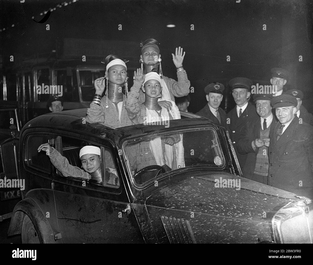 Sie fanden das Sonnendach unschätzbar. Giraffen Hals Frauen kommen in London. Eine Reihe von Giraffen necked Frauen von Burma angekommen Victoria Station von Paris zu Bertram Mills Zirkus auf seiner Sommer "Tenting" Tour zu verbinden. Die durchschnittliche Länge des Halses erreicht bis zu sechzehn Zoll. Die Padaung Mutter dehnt ihr weibliches Kind ' s Hals allmählich durch Hinzufügen eines Rings evey Jahr und auch Ringe an den Beinen. Die Menge des Metalls trägt einen definierten Heiratswert. Foto zeigt, Giraffe necked Frauen von Burma finden das Sonnendach ihres Autos bequem, wie sie einen Blick auf London nehmen. 1. März 31 Stockfoto