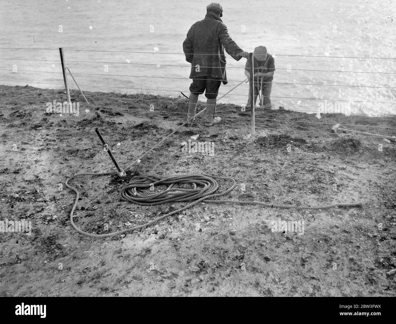 Klippenscheren an Seilen befestigt bei der Arbeit hoch über den Wellen in Rottingdean Clearing gefährliche überhängende Felsen über dem Strandweg . Februar 1935 Stockfoto