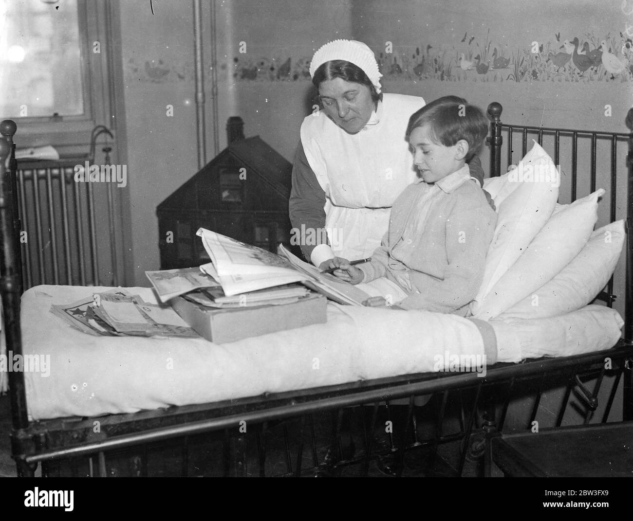 Kleiner Junge, der gelernt, im Krankenhaus zu zeichnen, um in die Schule geschickt werden. Tommy Milner Zeichnung im Bett am University College Hospital von Schwester Hantsch beobachtet. Februar 1935 Stockfoto