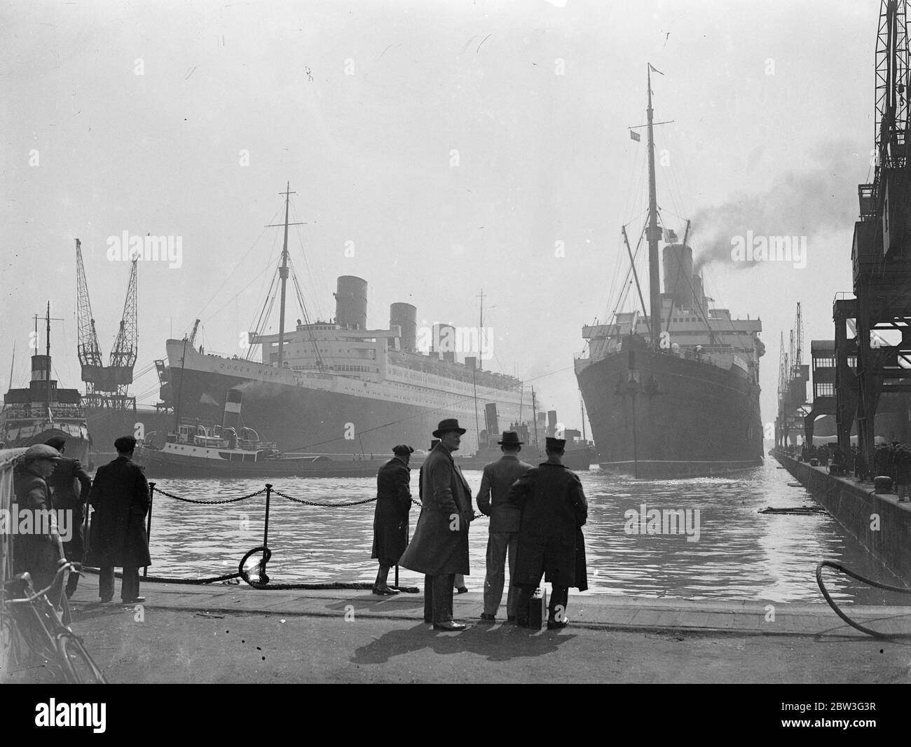 Altes und neues Flaggschiff der Cunard White Star Flotte treffen sich in Southampton. Die alten und neuen Flaggschiffe der Cunard White Star Flotte trafen sich in Southampton, als die "Berengaria", die aus Amerika zurückkehrte, neben dem riesigen Linienschiff "Queen Mary" im Ocean Dock andockte. Commodore Sir Edgar Britten, der die "Queen Mary" befehligen soll, war früher das Kommando über "Berengaria". Foto zeigt, Berengaria Andocken neben der Queen Mary in Southampton. 10. April 1936 Stockfoto