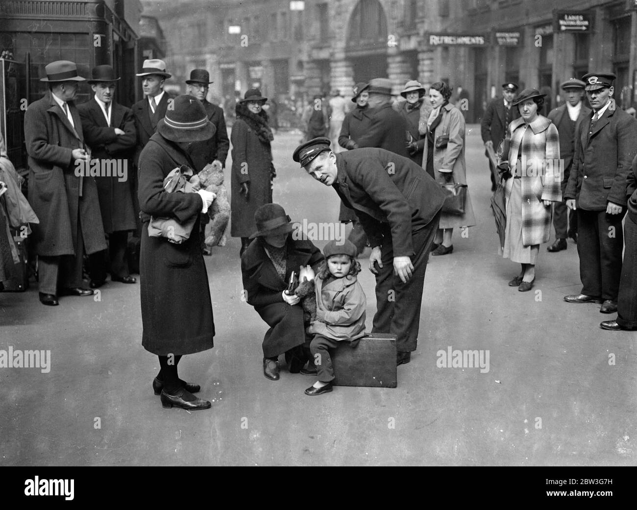 Warten auf den Urlaub Zug . Der große Bahnhof von London befindet sich jetzt auf dem Höhepunkt des Osterrausches. Tausende von Londonern verlassen die Metropole, um ein paar Tage im Land oder an Badeorten zu verbringen. Foto zeigt, zwei kleine Reisende in Waterloo diskutieren das Thema Urlaub mit einem Portier. 11. April 1936 Stockfoto