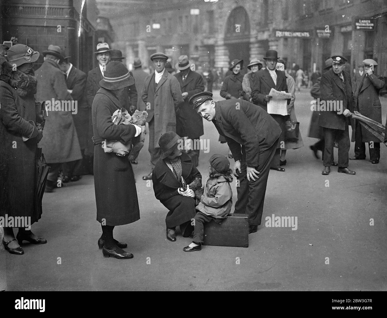 Warten auf den Urlaub Zug . Der große Bahnhof von London befindet sich jetzt auf dem Höhepunkt des Osterrausches. Tausende von Londonern verlassen die Metropole, um ein paar Tage im Land oder an Badeorten zu verbringen. Foto zeigt, zwei kleine Reisende in Waterloo diskutieren das Thema Urlaub mit einem Portier. 11. April 1936 Stockfoto