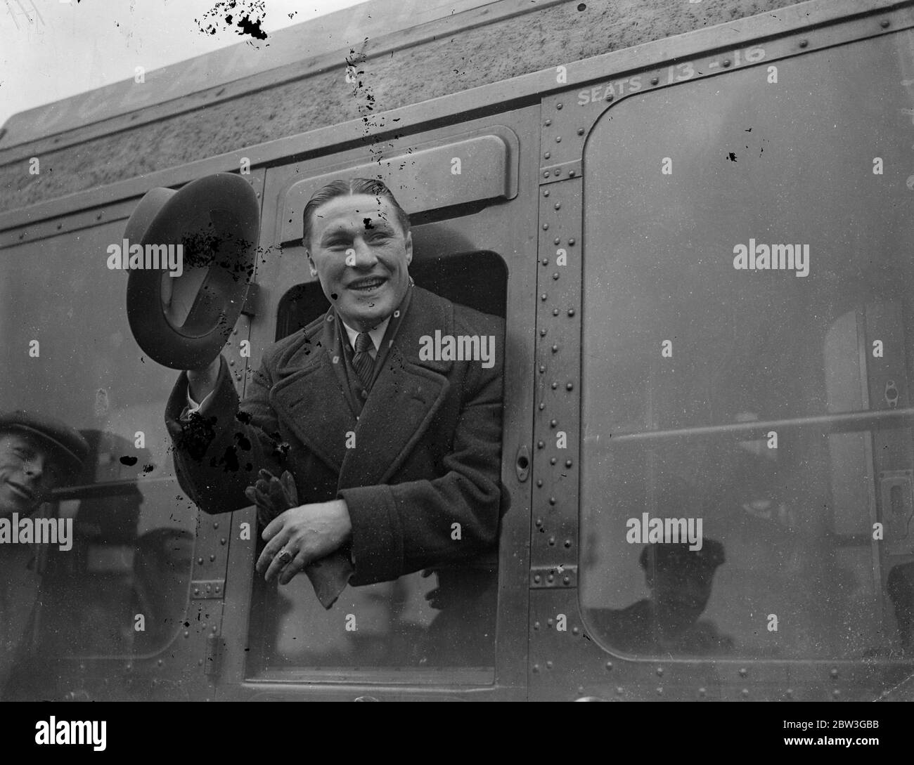 Tommy Loughran, ehemaliger amerikanischer Inhaber der Welt-Leichtgewicht-Boxmeisterschaft, verließ Waterloo auf dem Aquitania-Bootszug, um in die Vereinigten Staaten zurückzukehren. Foto zeigt, Tommy Loughran winkte auf Wiedersehen, als er Waterloo verließ. April 1936 Stockfoto