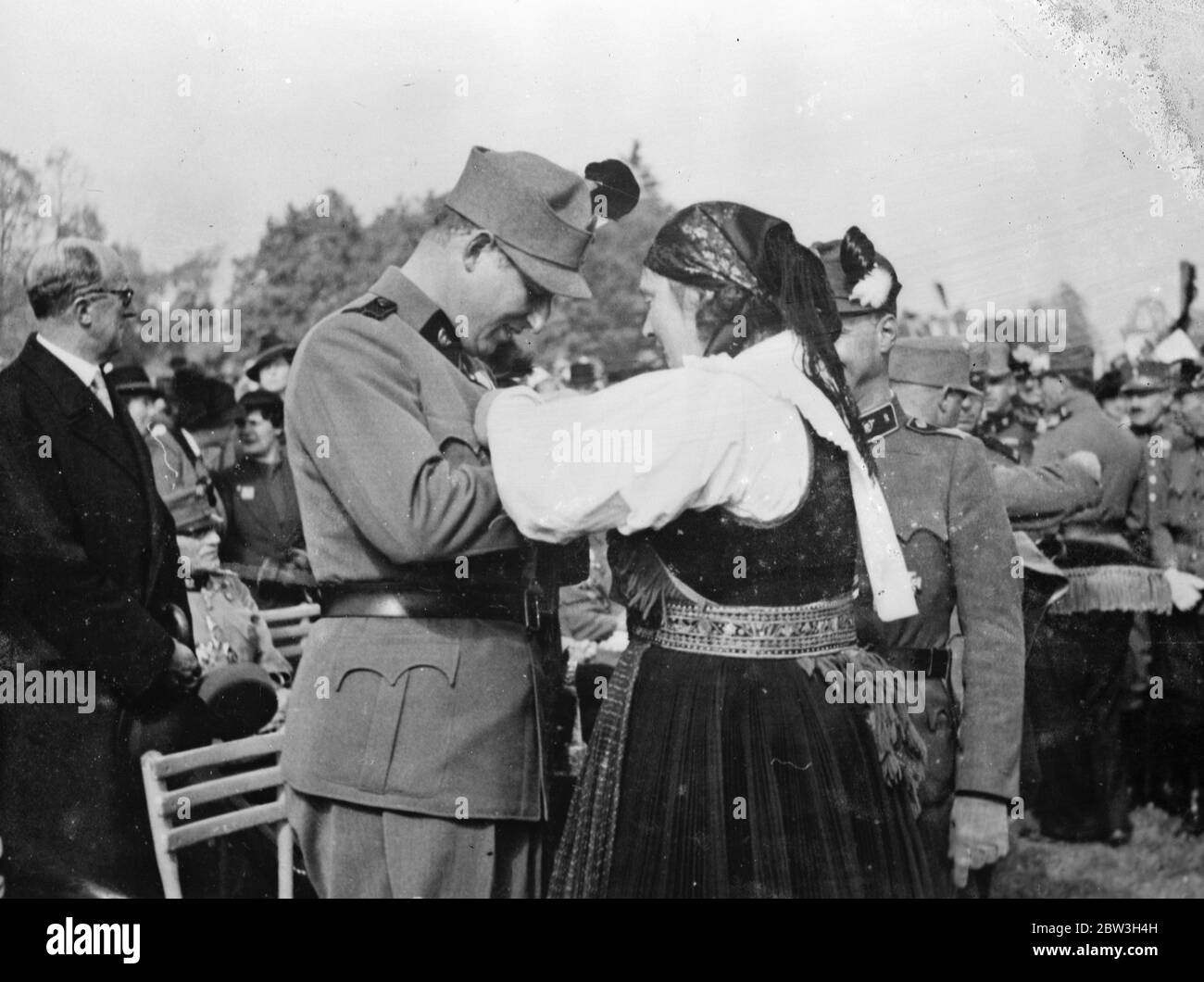 Ein Knopfloch für den Prinzen. Prinz Starhemberg, Vizekanzler von Österreich, erhält lächelnd ein Knopfloch von einer Bäuerin, als er an einem Militärgedenkplatz in Klegenfurt in Kärnten teilnahm. 12. Oktober 1935 Stockfoto