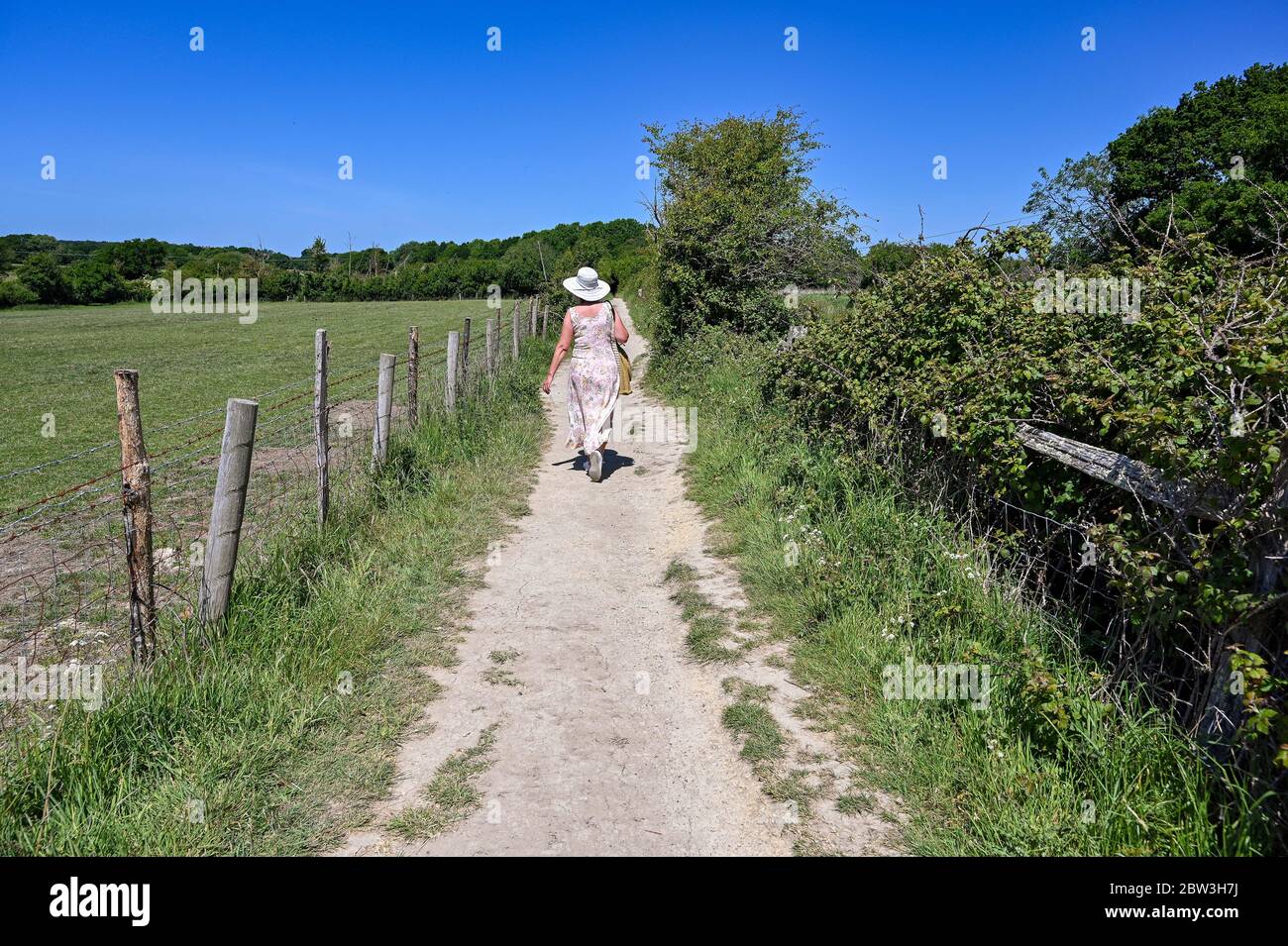 Eastbourne UK 29. Mai 2020 - EINE Frau genießt einen Spaziergang auf einem ausgetrockneten Weg rund um Arlington Reservoir in der Nähe von Eastbourne in Sussex an einem heißen sonnigen Tag während der Coronavirus COVID-19 Pandemie Krise . Dies war einer der trockensten Mai Monate in Großbritannien seit Beginn der Aufzeichnungen. Quelle: Simon Dack / Alamy Live News Stockfoto