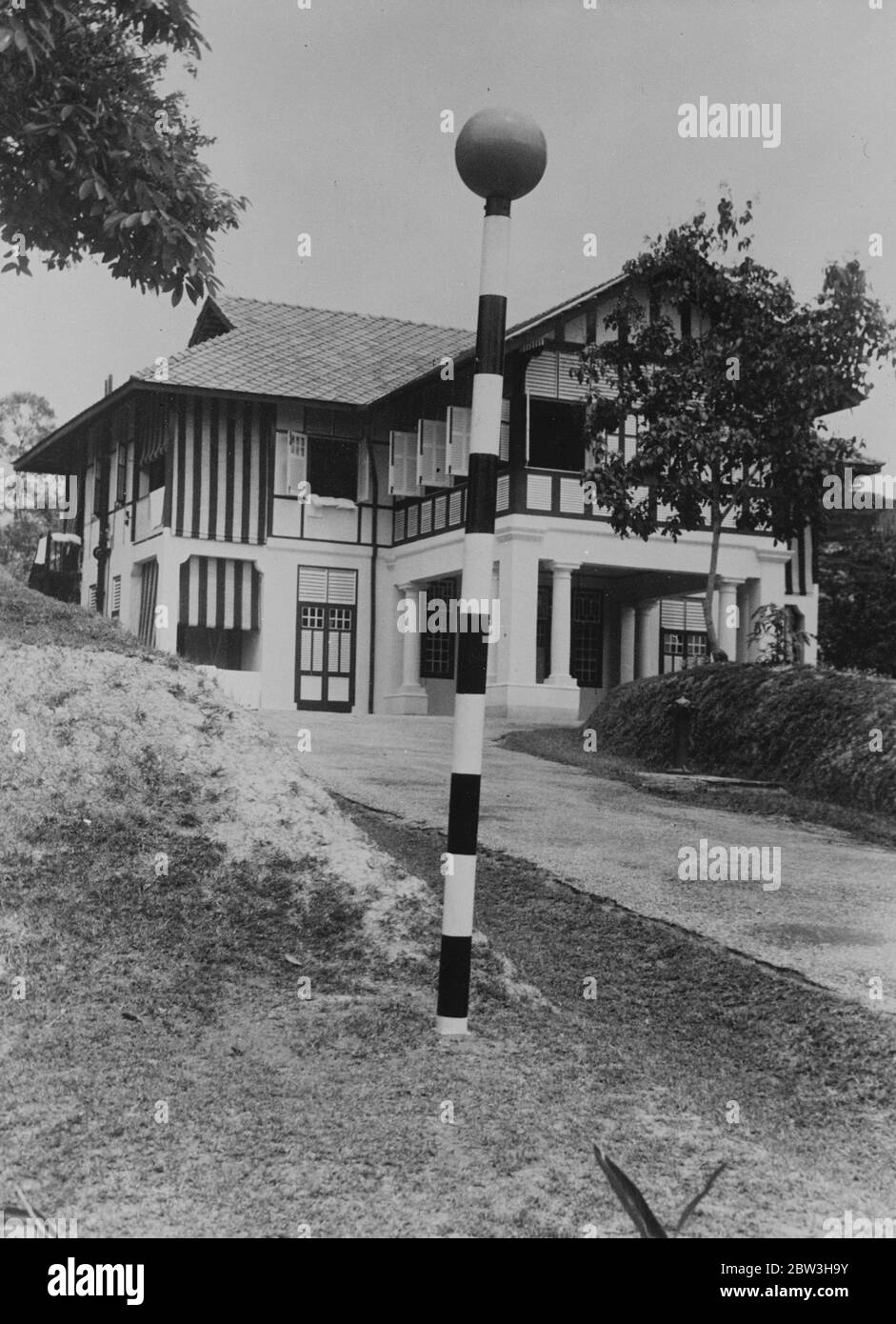 Belisha ist minus ein Leuchtturm. Der Belisha Beacon, strahlend in neuer Farbe, stehend in einsamen Zustand im Garten eines Singapurhauses. 20. November 1935 Stockfoto