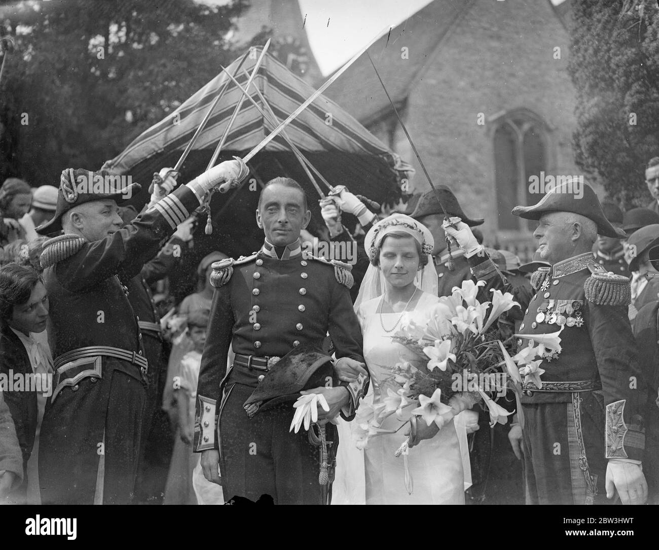 Schneider ziehen Brautwagen von der Kirche bei Naval Hochzeit in Kent Dorf. Schneider schleppte das Brautauto aus der Kirche, als Lieutenant Commander John Harry Boughton, war verheiratet mit Miss Esmee Katalin Lowther in der Pfarrkirche von Loose, Kent. Foto zeigt, die Braut und Bräutigam verlassen durch die Marine Garde der Ehre. 30 Juli 1936 Stockfoto