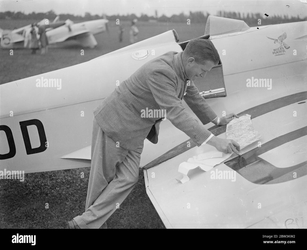 Tommy Rose tritt im King's Cup Air Race an. King ' s Cup-Luftrennen startete von Hatfield Aerodrome. Es gibt 28 Einträge . Der erste der beiden Tage des Wettbewerbs nimmt die Form der Beseitigung in einem Rennen über zwei Schaltungen von einem Kurs von 612 Meilen , was 1,224 Meilen in allen . Fünfzig Prozent der Starter in jeder der drei Flugzeuggruppen werden ins Finale gehen. Foto zeigt: Flug - Leutnant Tommy Rose Studium einer Karte auf dem Flügel seiner Miles Hawk Flugzeug in Hatfield. Juli 1936, 10 Stockfoto