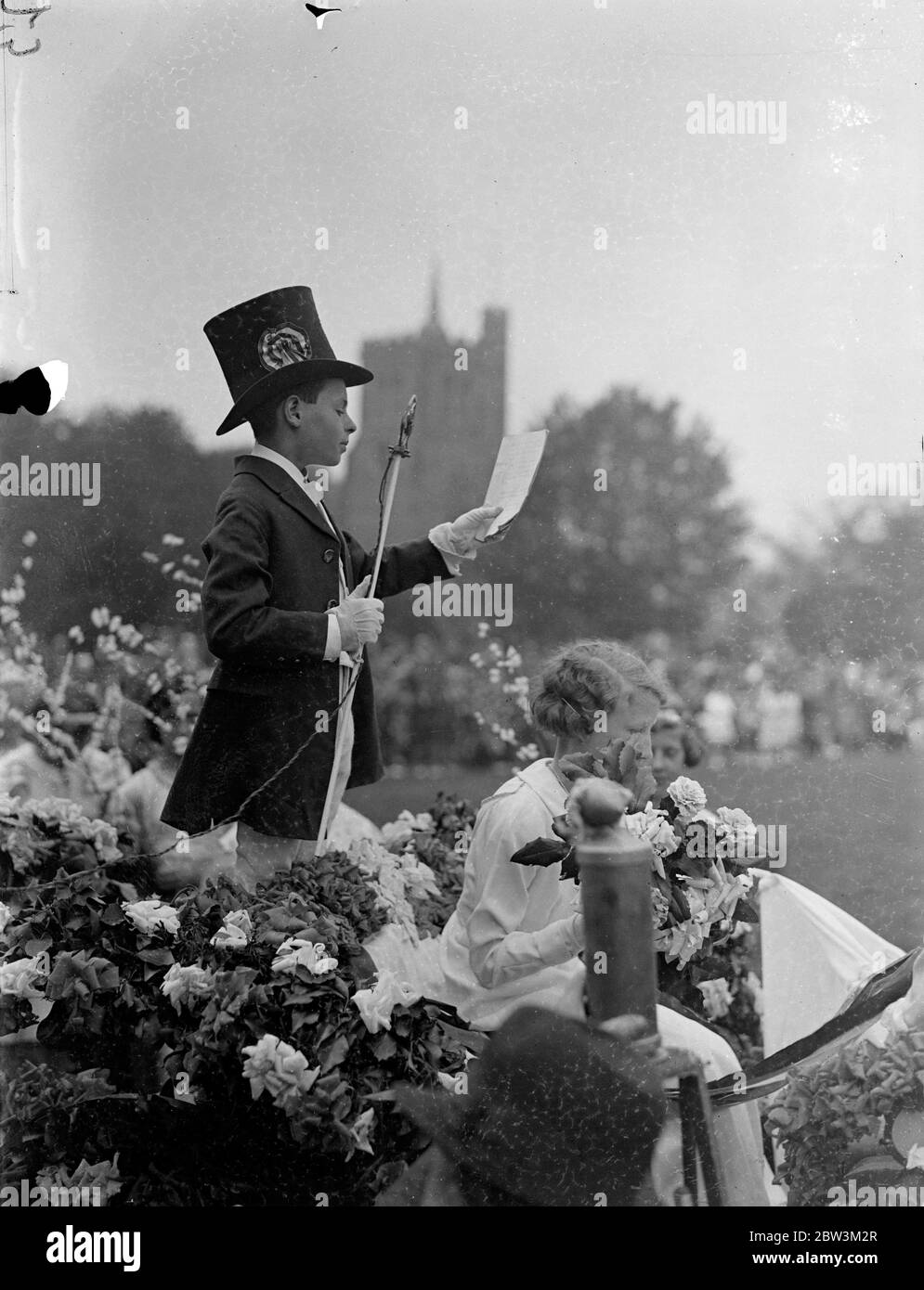 Mai Königin gekrönt in einem Bedfordshire Dorf. Modernes Mikrofon-Bophon bei traditioneller Zeremonie. Nach einer Prozession durch die Straßen zu Elstow Green, Miss Betty Crouch wurde gekrönt May Queen in Elstow, Bedfordshire, Geburtsort von John Bunyan. Die Zeremonie beinhaltete Maibaum und Landtänze. Die Krönung wurde von Phyllis Izzard durchgeführt, im vergangenen Jahr 's May Queen. Foto zeigt, die "Proklamation" wird in ein modernes Mikrofon gelesen. Mai 1936 Stockfoto