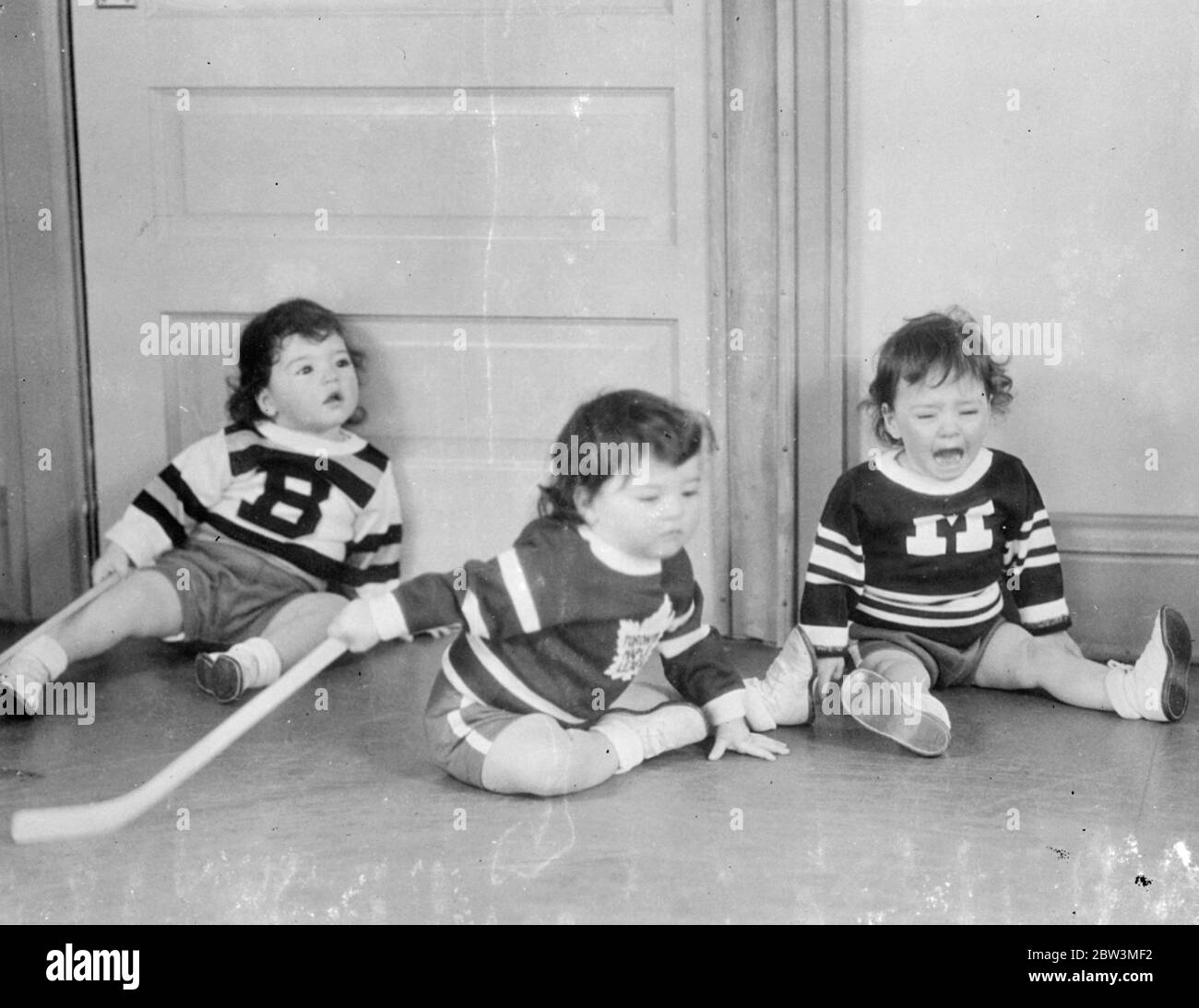 Eishockey ist ein Wunde Punkt mit Marie! . Spill in der Quins Kindergarten . Eishockey auf der Kinderstube, die ' s die Dionne Quintuplets neuesten Zeitvertreib, und ganz natürlich auch, für wen von einem Kanadier, der nicht interessiert war, Eishockey im fortgeschrittenen Alter von fast zwei Jahren gehört. Obwohl sie manchmal zwischen dem rechten Ende des Stockes und dem falschen verwechselt werden, haben die Quins wirklich eine aufregende Zeit, aber der Glanz des schön polierten Bodens leidet meist! . Foto zeigt, Marie in einer Montreal Maroon Uniform, löst sich in Tränen nach einem Spill auf dem Kinderzimmer Boden bei Callender, Stockfoto