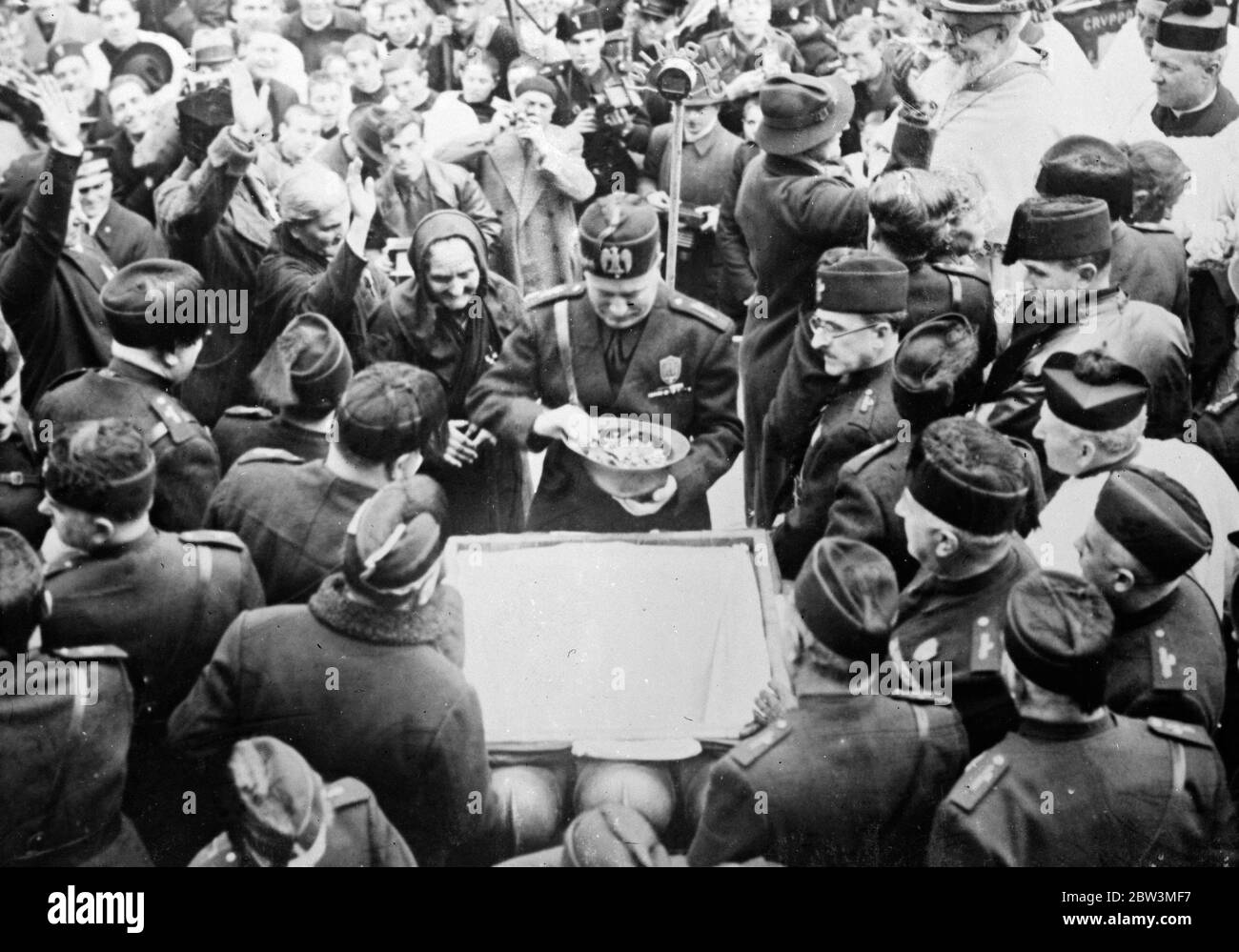 Mussolini sagt, dass der Krieg bis zum Ende geführt wird - Mütter präsentieren Schmuckstücke zu verführen. Signor Mussolini mit dem Helm gefüllt mit Schmuckstücken, die er von den alten Frauen auf der linken Seite erhalten hatte. 20 Dezember 1935 Stockfoto