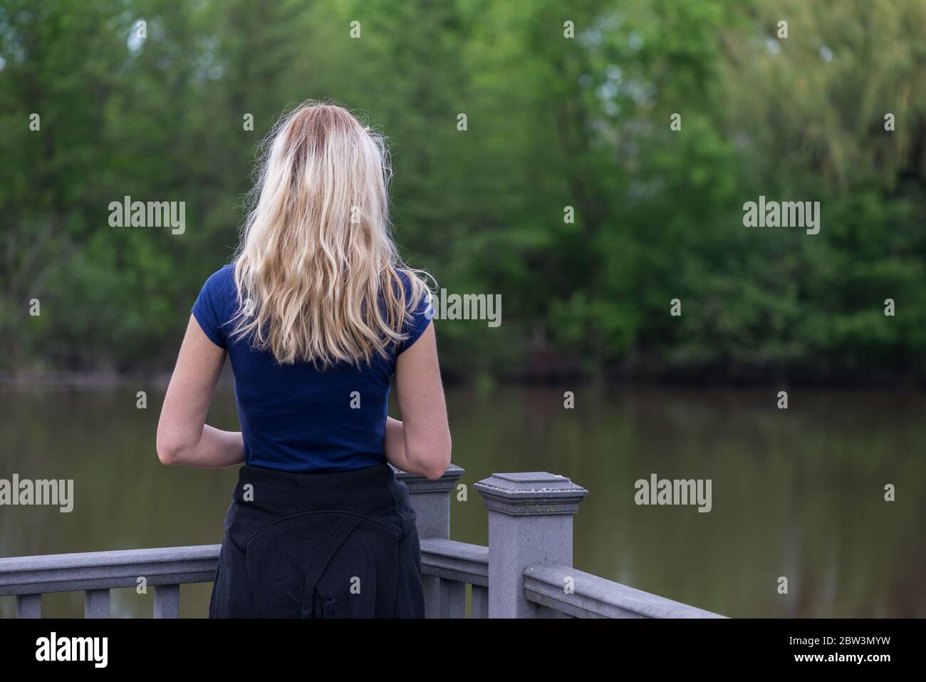 Frau, die auf den See und die Bäume schaut Stockfoto