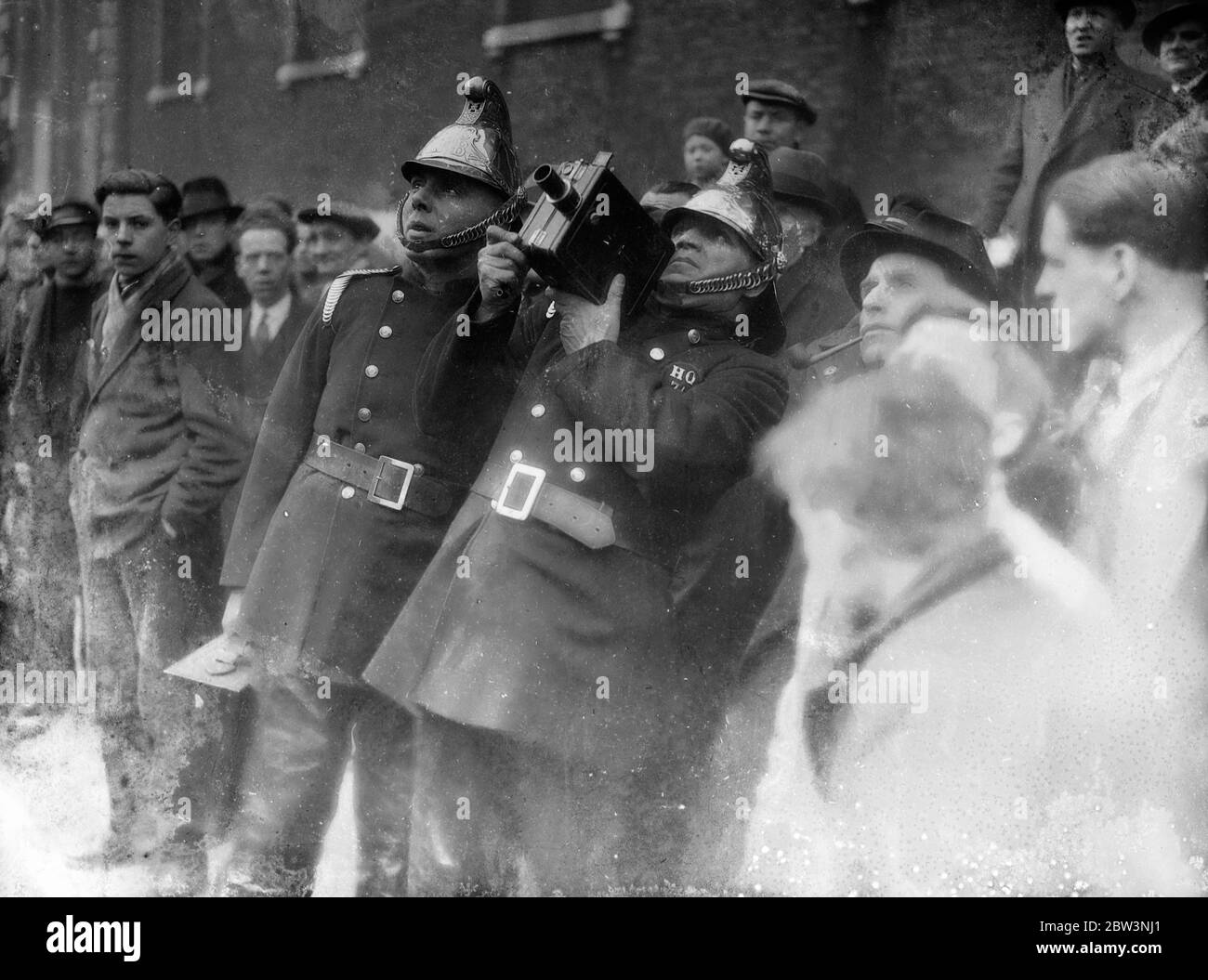 Feuerwehrleute Film und Kampf lodern bei Clerkenwell . Die Feuerwehr filmte die Flamme, als ein Feuer auf einem Möbeldepisant in Clerkenwell Green, London ausbrach. Die Idee wurde kürzlich von der Londoner Feuerwehr übernommen und bei allen großen Bränden wird ein Film gedreht. Foto zeigt, ein Feuerwehrmann filmt die Flamme bei Clerkemwell. 12 Februar 1936 Stockfoto