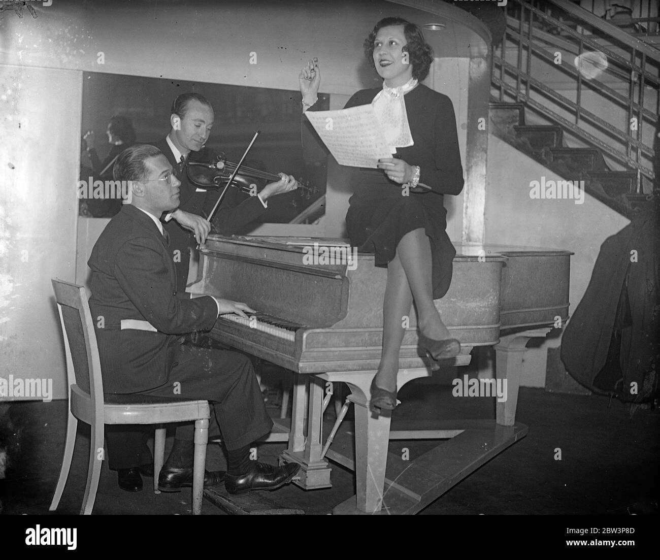 Chaplins ehemalige Frau probt für den ersten Auftritt auf der Londoner Bühne. Lits Grey, zweite Frau von Charlie Chaplin und Mutter seiner beiden Kinder, probt in London für ihren ersten Auftritt auf der Londoner Bühne. Foto zeigt, Lita Grey Proben mit ihrem Pianisten, Irving Actmen und Jock Harris, der Tanzkapelle-Leiterin, für ihren ersten Auftritt auf der Londoner Bühne. Dezember 1935 Stockfoto