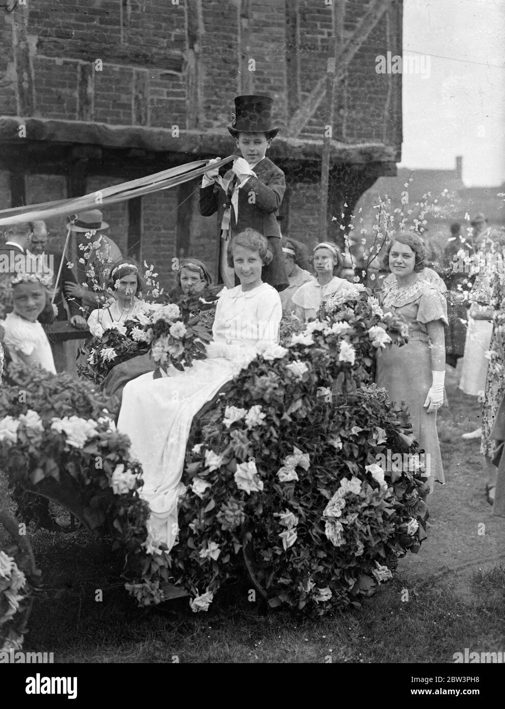 Mai Königin gekrönt in einem Bedfordshire Dorf. Modernes Mikrofon-Bophon bei traditioneller Zeremonie. Nach einer Prozession durch die Straßen zu Elstow Green, Miss Betty Crouch wurde gekrönt May Queen in Elstow, Bedfordshire, Geburtsort von John Bunyan. Die Zeremonie beinhaltete Maibaum und Landtänze. Die Krönung wurde von Phyllis Izzard durchgeführt, im vergangenen Jahr 's May Queen. Foto zeigt, die "Proklamation" wird in ein modernes Mikrofon gelesen. Mai 1936 Stockfoto