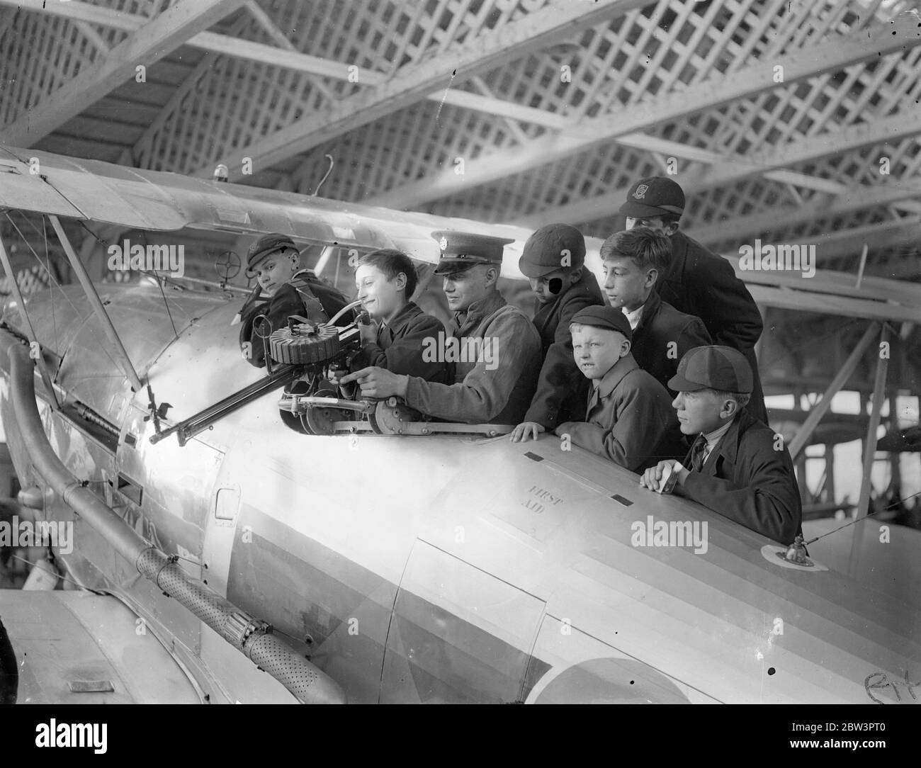 Schüler sondieren die Arbeiten eines Kampffuchs am Empire Air Day in Hendon. Große Menschenmengen, darunter viele Kinder, sahen die Empire Air Day-Ausstellung im Hendon Aerodrome. Das 11. London Regiment (die Finsbury Gewehre), das jetzt die 170 und 171 Anto Flugzeugbatterien umfasst, kooperierte mit der Royal Air Force im Display. Foto zeigt, Schüler experimentieren mit dem Lewis Kanonenring in einem Hawker Demon Fighter. 23 Mai 1936 Stockfoto