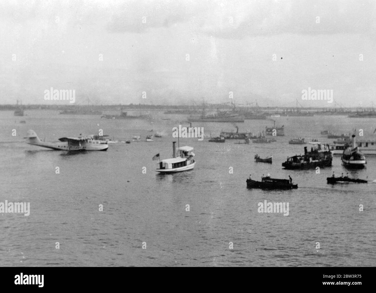 China Clipper kommt nach dem ersten trans Pacific Air Mail Flug in Manila an. Die China Clipper Taxi-ing zum Landekahn nach ihrer Ankunft in Manila . In der Ferne amerikanische Kriegsschiffe können in Galakleid gesehen werden. 19 Dezember 1935 Stockfoto