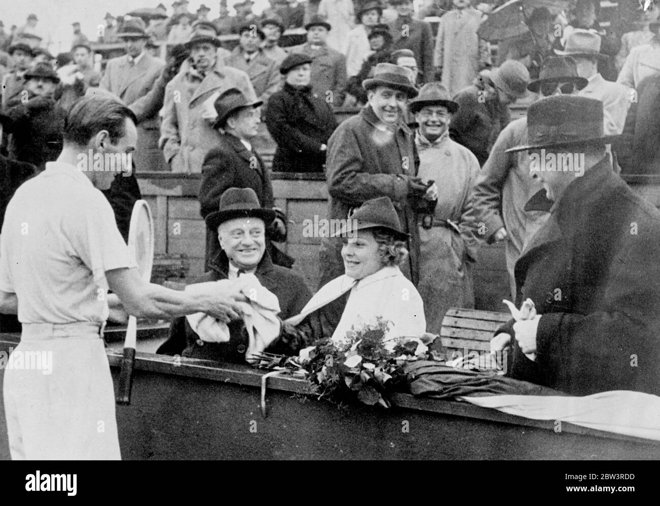 Frau Perry lächelte siegreichen Ehemann in Prag . Britischer Meister gewinnt tschechischen Titel . F J Perry gewann die Einzel-Meisterschaft der Tschechoslowakei in Prag durch Sieg gegen L Hecht , die tschechische Davis-Cup-Spieler , von 6 - 2 , 6 - 3 , 4 - 6 und 6 - 1 im Finale . Foto zeigt, Perry reagiert auf das Lächeln seiner Frau, Helen Vinson, die Filmschauspielerin, wie sie ihm seinen Pullover nach seinem Sieg reicht. 25. April 1936 Stockfoto