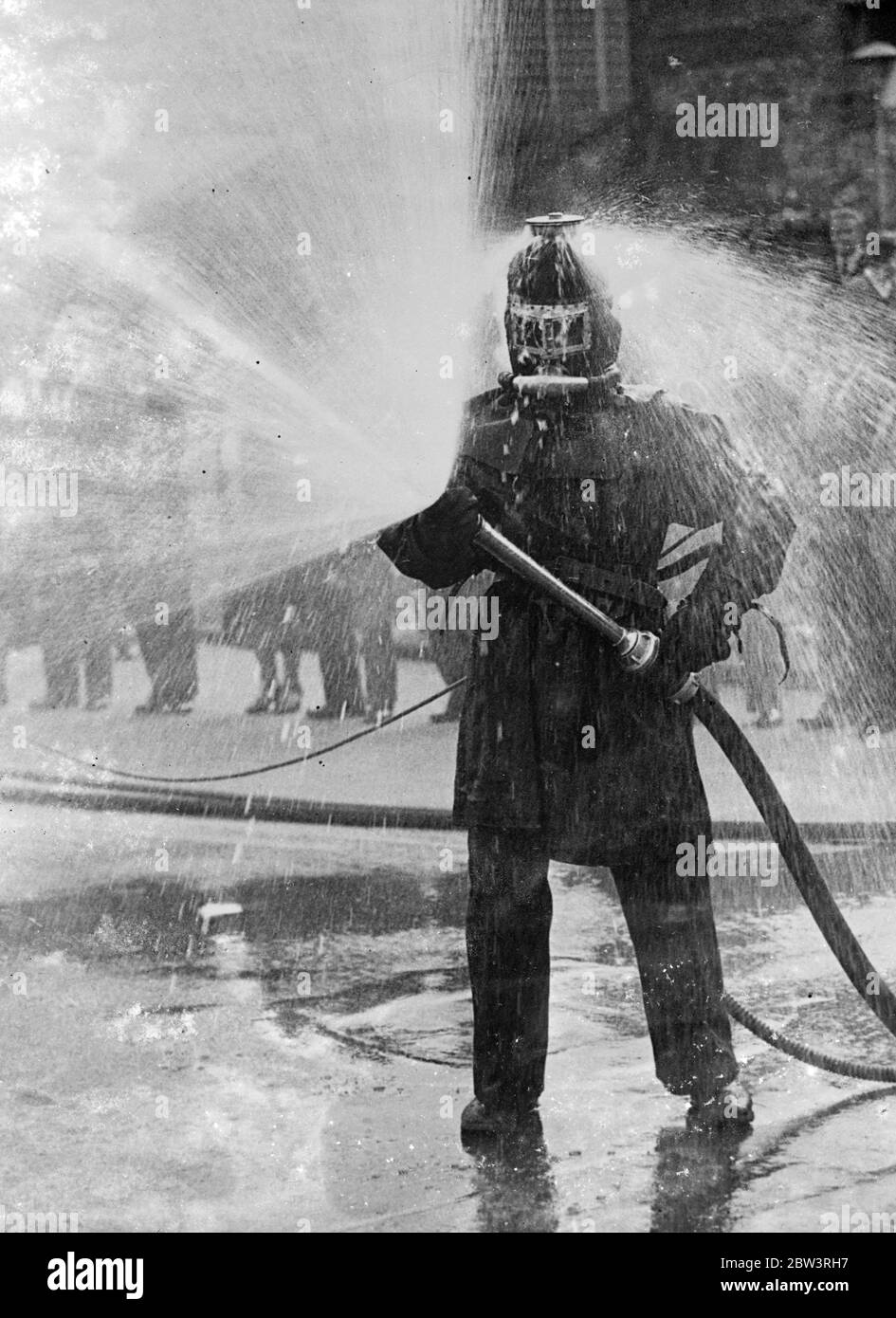 Feuer - Beweis Anzug, Der Hilft, Flammen Zu Bekämpfen. Besonders Nützlich Bei Luftangriffen . Ein Feuerschutzanzug, der bei der Bekämpfung von Flammen eine Rolle spielt und speziell für den Einsatz bei Luftangriffen entwickelt wurde, wurde auf der Deutschen Münz-Ausstellung in Berlin gezeigt. Der Anzug umschließt den Träger von Kopf bis Fuß, die Oberseite des Helms wirft einen starken Wasserstrahl. Dies ermöglicht es dem Feuerjäger, viel näher an die Flamme zu kommen als sonst. Foto zeigt: Der neue Feueranzug im Einsatz. Wasser kann von der Oberseite des Helms sprudeln gesehen werden. 11 Juni 1936 Stockfoto