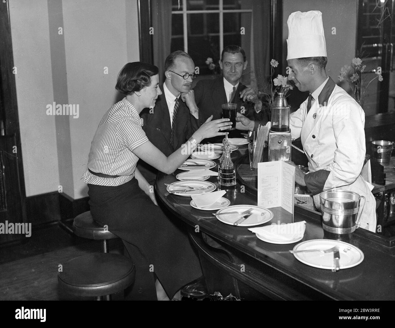 Britains erste Bahnhof Snack-Bar in Paddington eröffnet. Die erste Snack-Bar für Passagiere auf einem britischen Bahnhof wurde auf der Bahnsteig Nummer 1 am Bahnhof Paddington in London eröffnet. Die Bar ist von ungewöhnlicher Design. Es ist wie ein Pferdehuh geformt und bietet Sitzgelegenheiten um die Außenseite auf hohen grünen gekrönten verchromten Ständen für 27 Personen. August 1935 Stockfoto