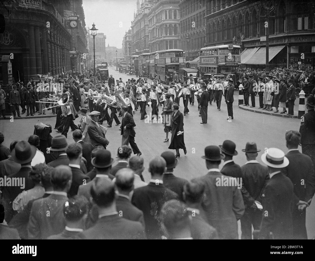 Vancouver Boys' Band Spielt Von St. Pauls ' s zum Mansion House. Die Vancouver Boys' Band, die für eine Tour nach Großbritannien gekommen sind, spielte sich von St. Paul ' s Kathedrale zum Herrenhaus, wo der Oberbürgermeister, Sir Percy Vincent unterhielt sie zum Tee. Die Band besteht aus 45 Jungs im Alter von 14 bis 19 Jahren. Foto zeigt: Der Verkehr hielt sich auf, als die Vancouver Boys' Band im Mansion House ankam. Juli 1936 Stockfoto